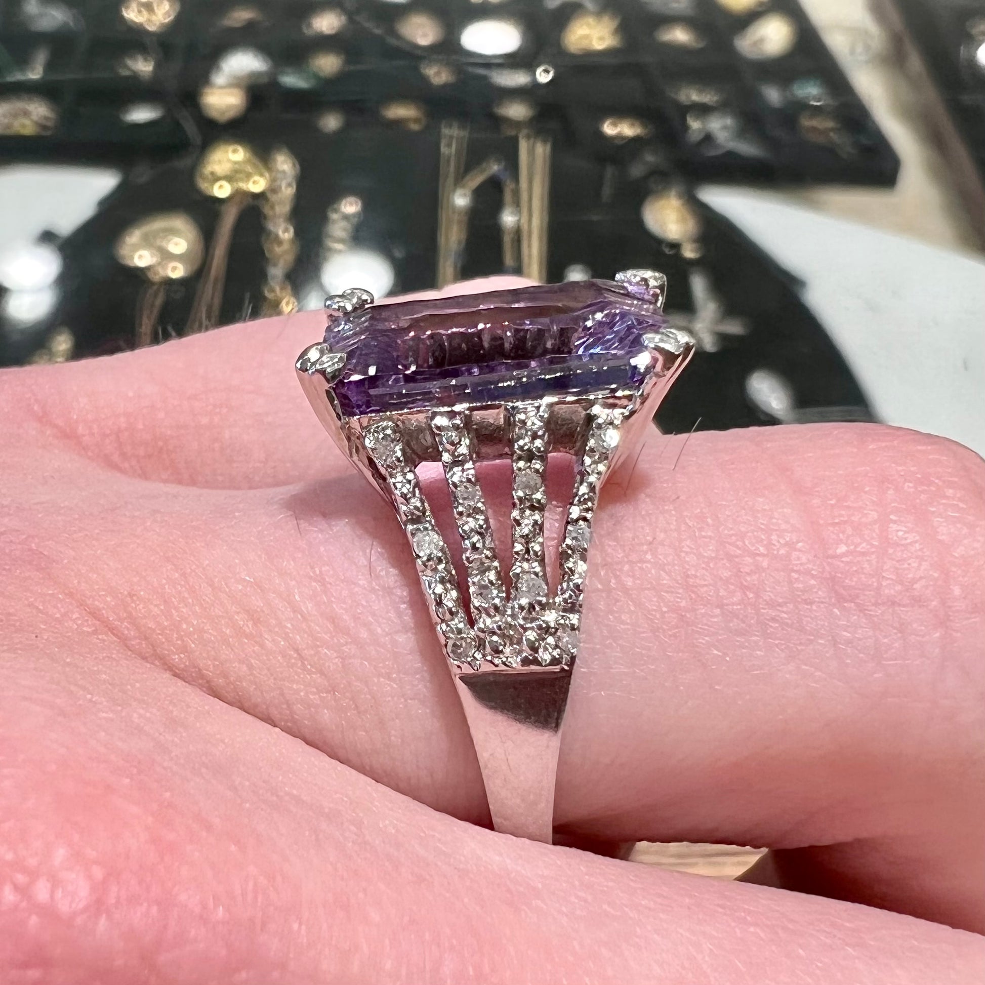 A white gold ladies ring set with an emerald laser cut amethyst and diamond chip accents.