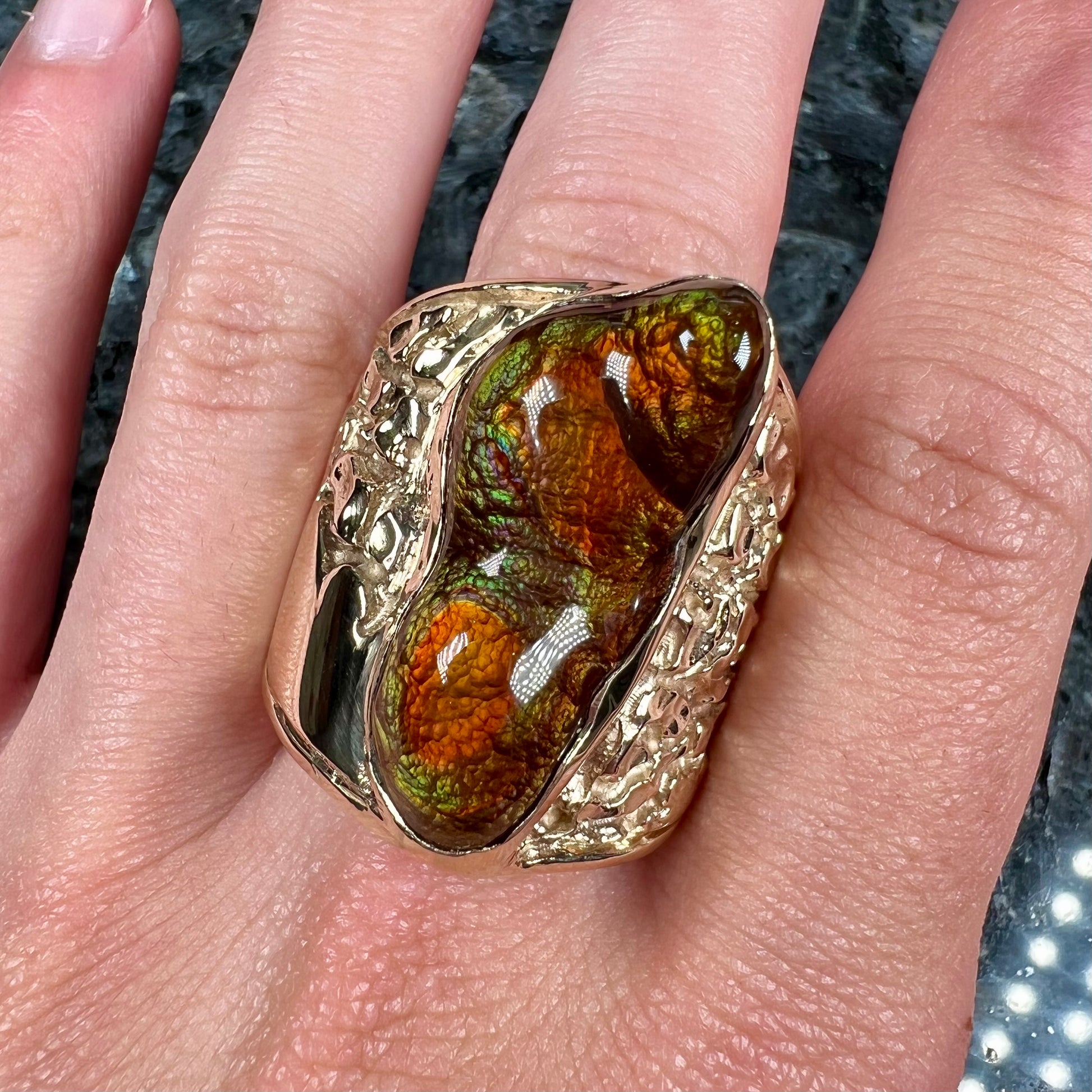 A large nugget style men's fire agate ring cast in yellow gold.  The fire agate is predominantly orange and green.