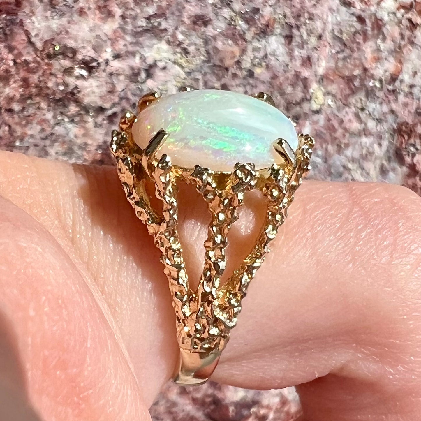 A yellow gold solitaire engagement ring set with an oval cabochon cut white crystal opal.
