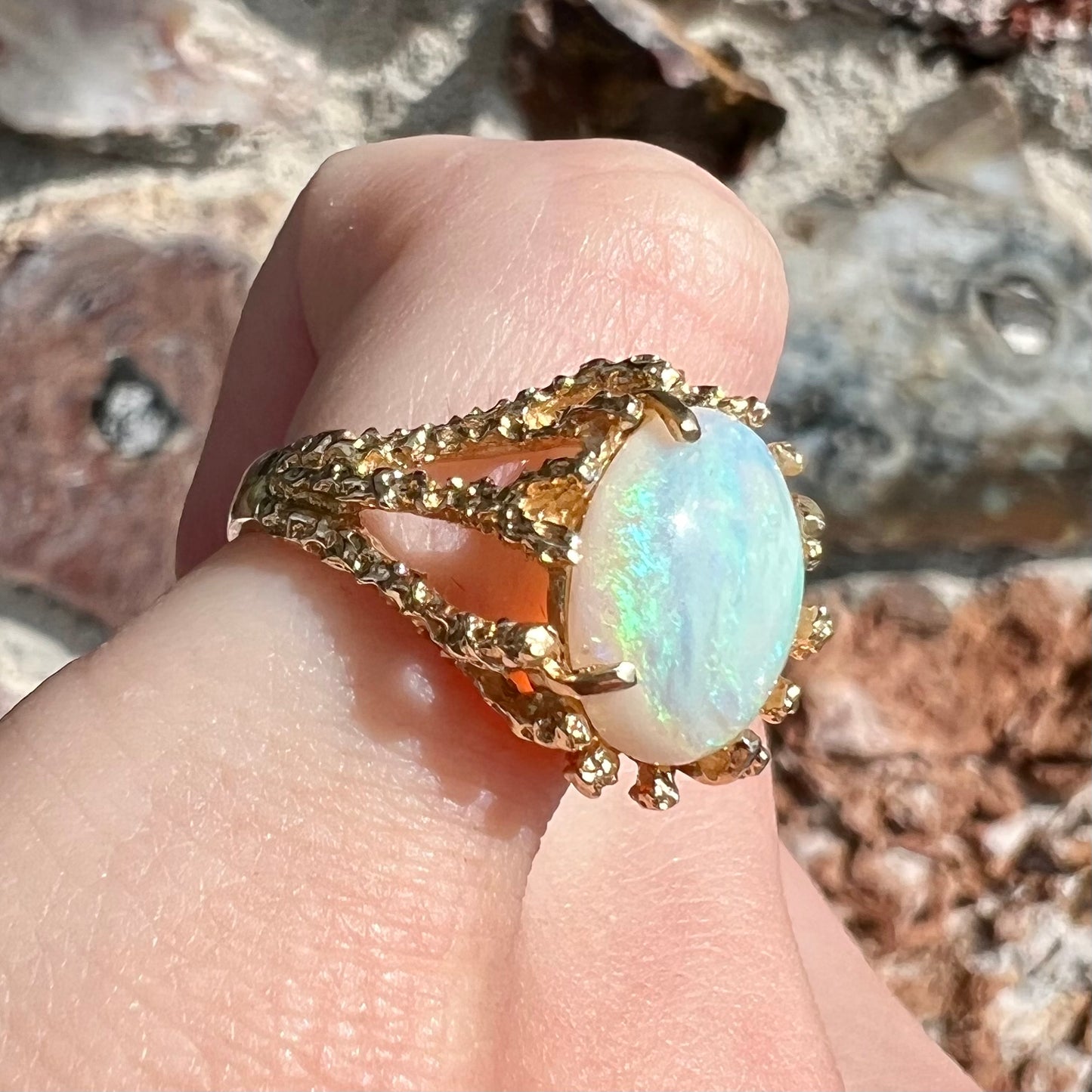 A yellow gold solitaire engagement ring set with an oval cabochon cut white crystal opal.
