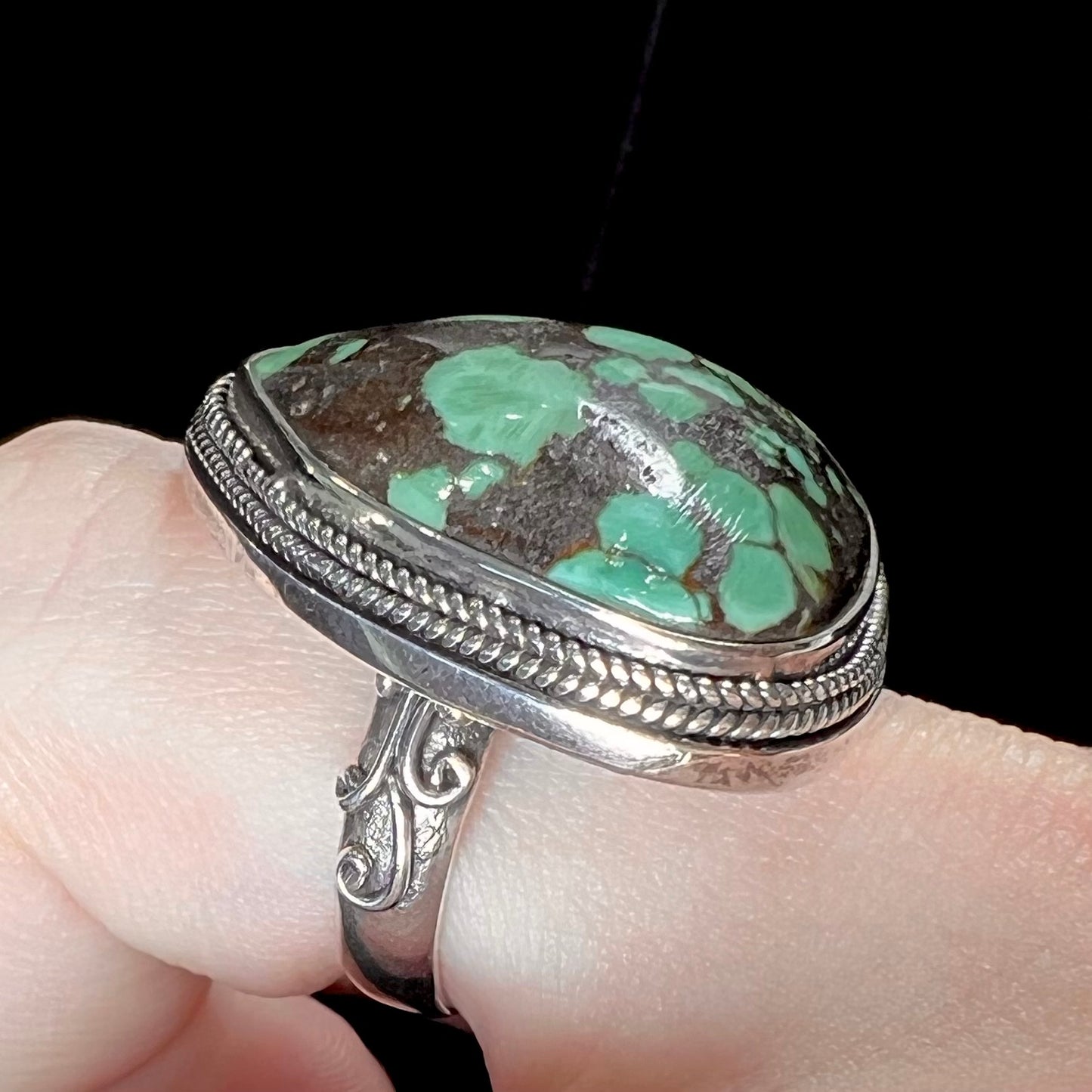 A sterling silver ring bezel set with a green spotted turquoise stone from Carico Lake, Nevada.