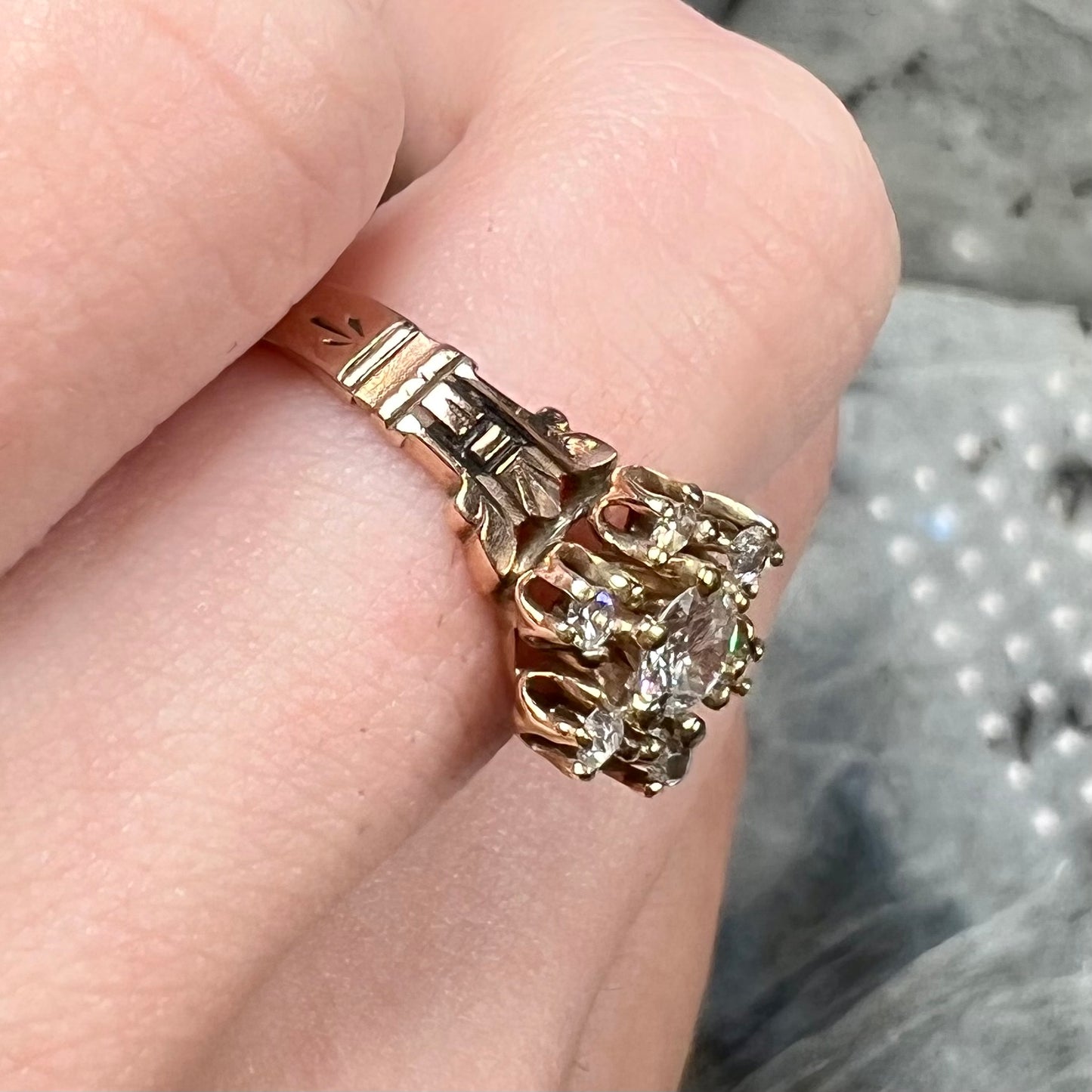 A modern Standard Round Brilliant Cut diamond set between six smaller round diamonds in an antique rose gold engagement ring setting.