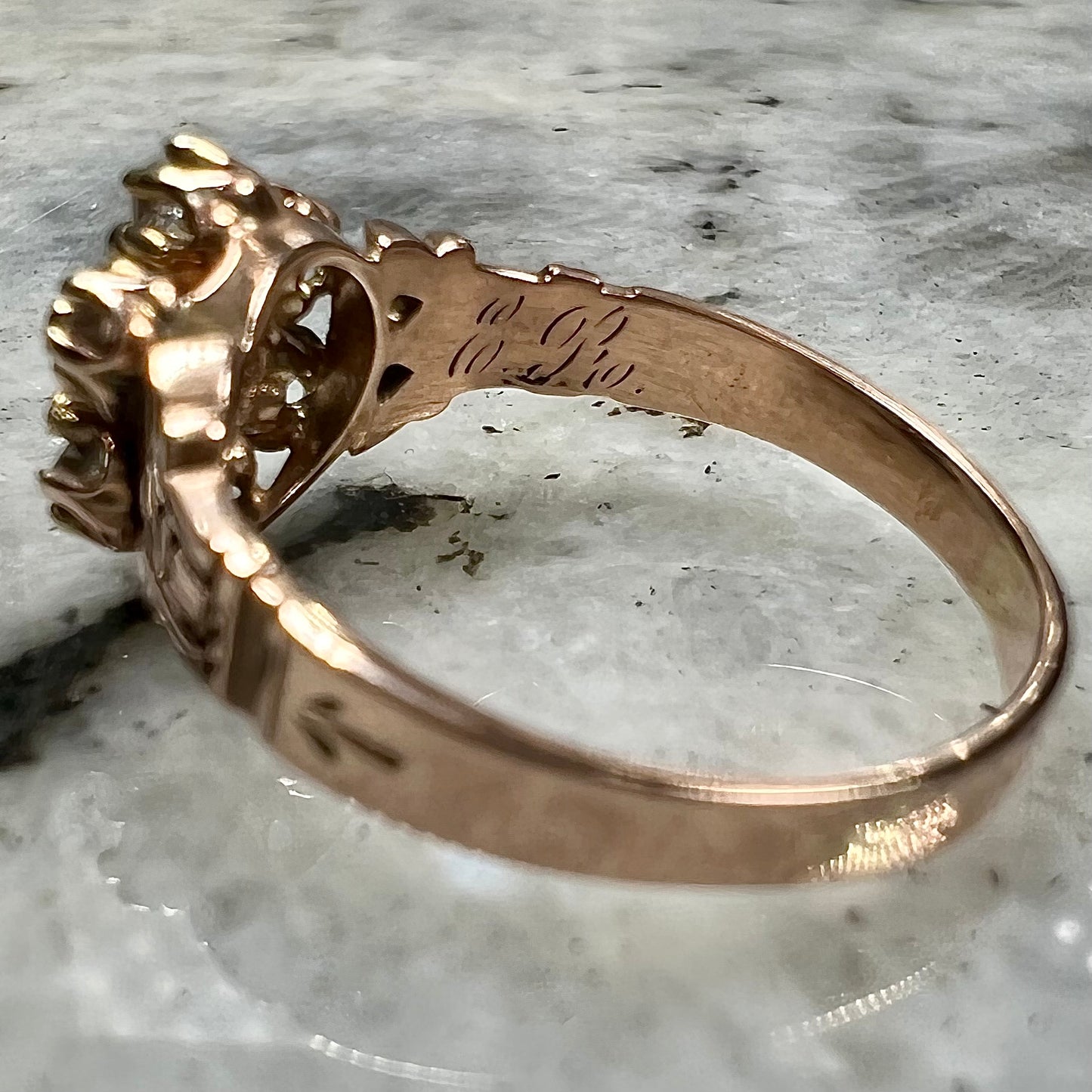 A modern Standard Round Brilliant Cut diamond set between six smaller round diamonds in an antique rose gold engagement ring setting.