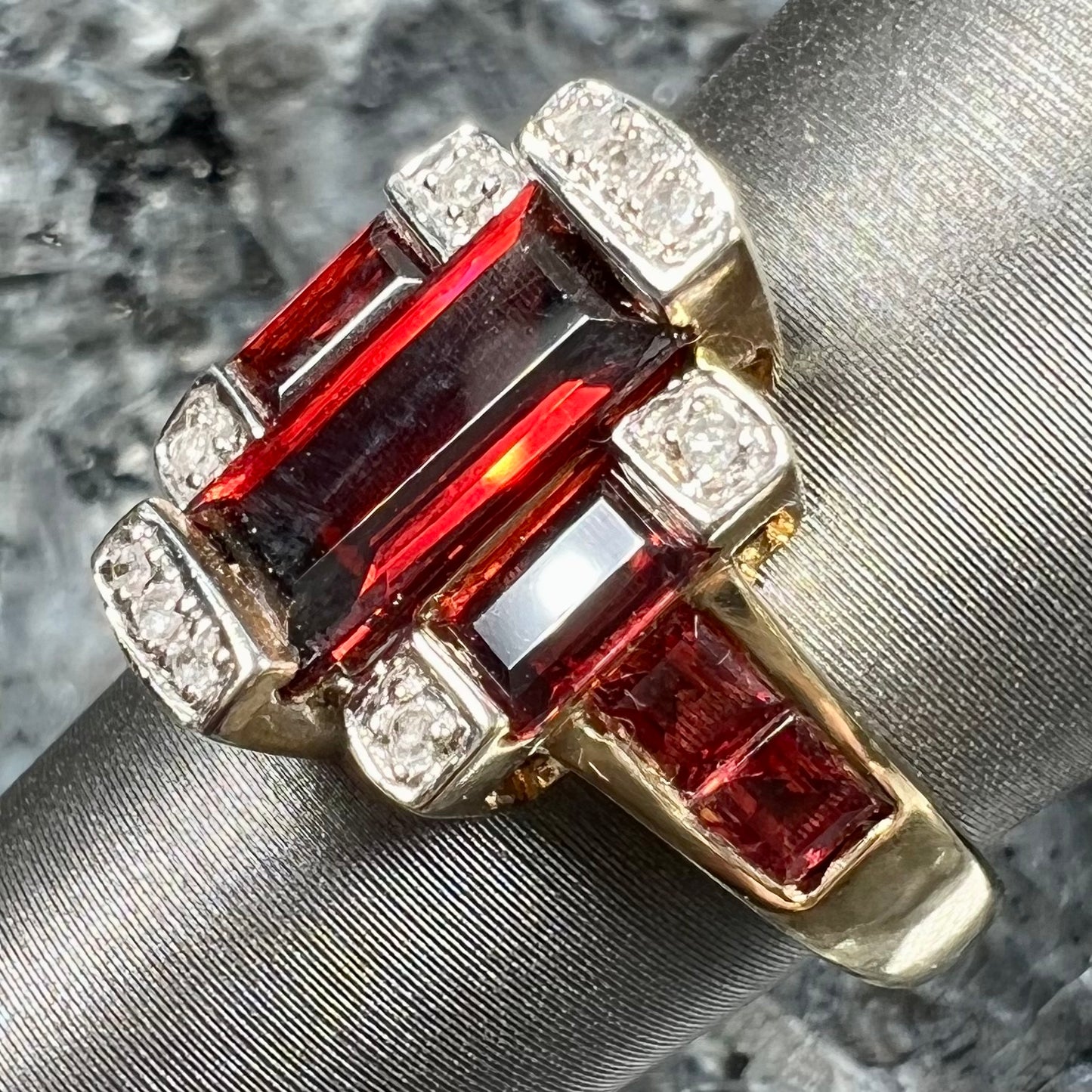 An Art Deco style emerald cut garnet and diamond ring cast in yellow gold.