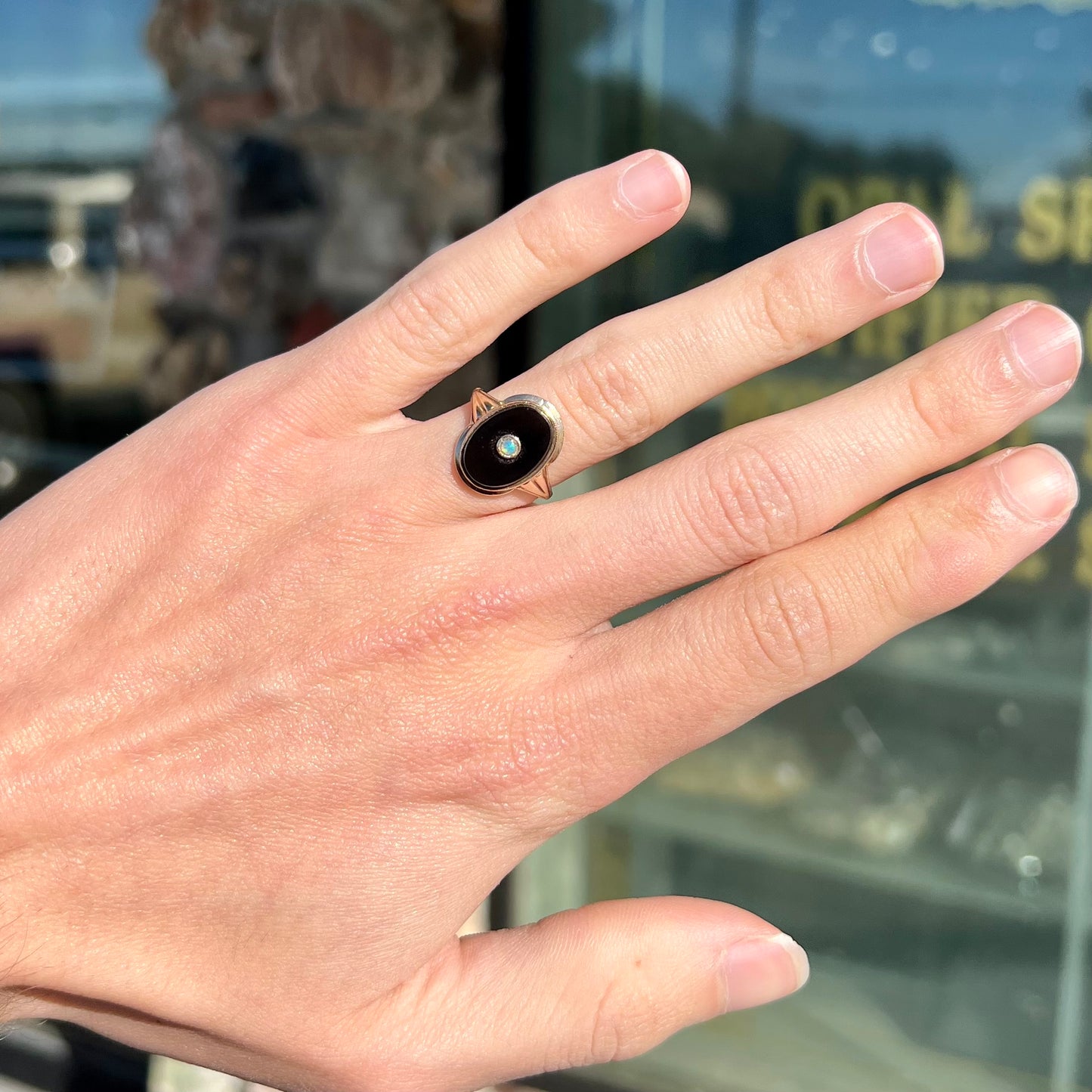 A yellow gold onyx ring set with a round cabochon cut opal bezel set into the onyx.