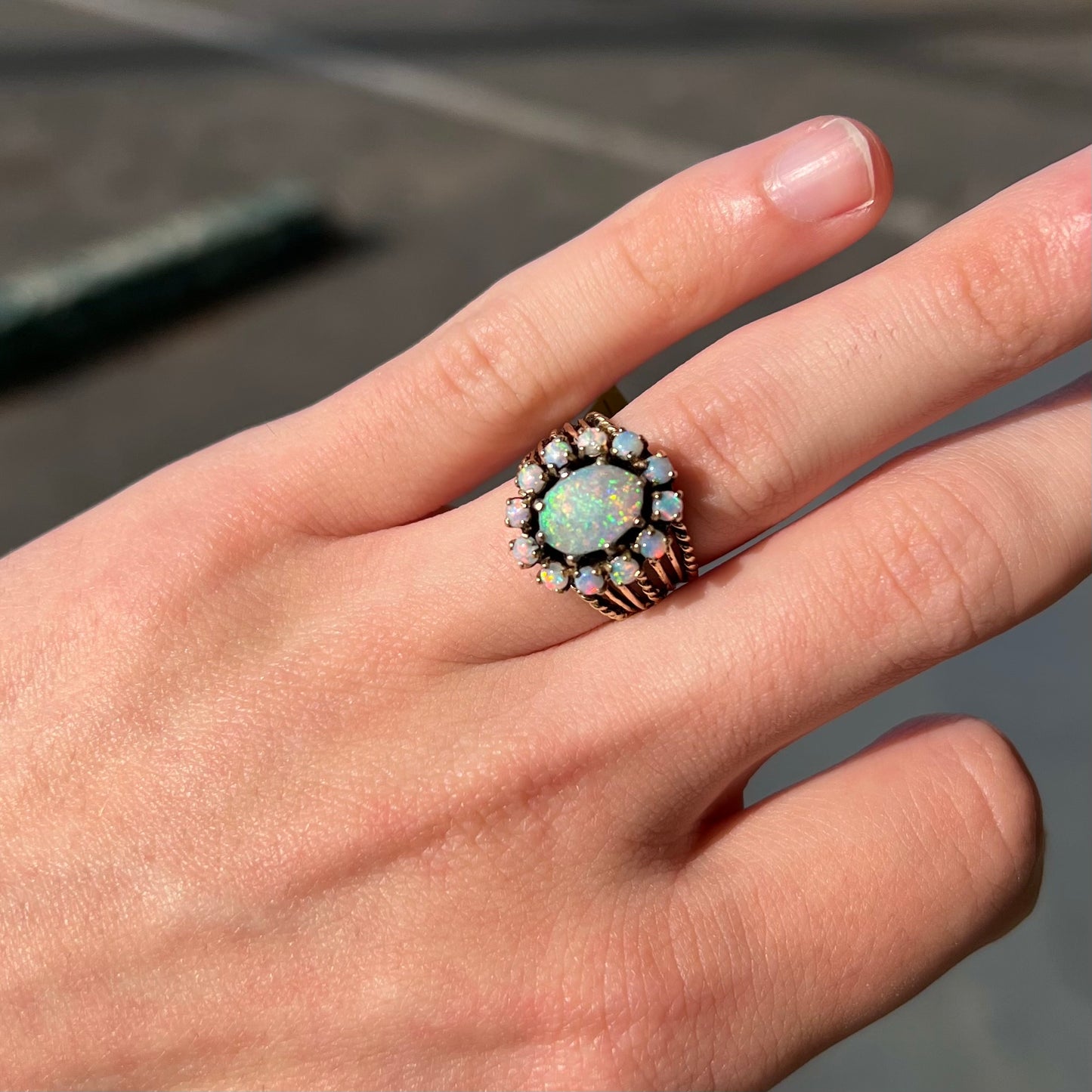 Vintage yellow gold oval opal cabochon ring set with 12 round opals in a halo around the center stone.