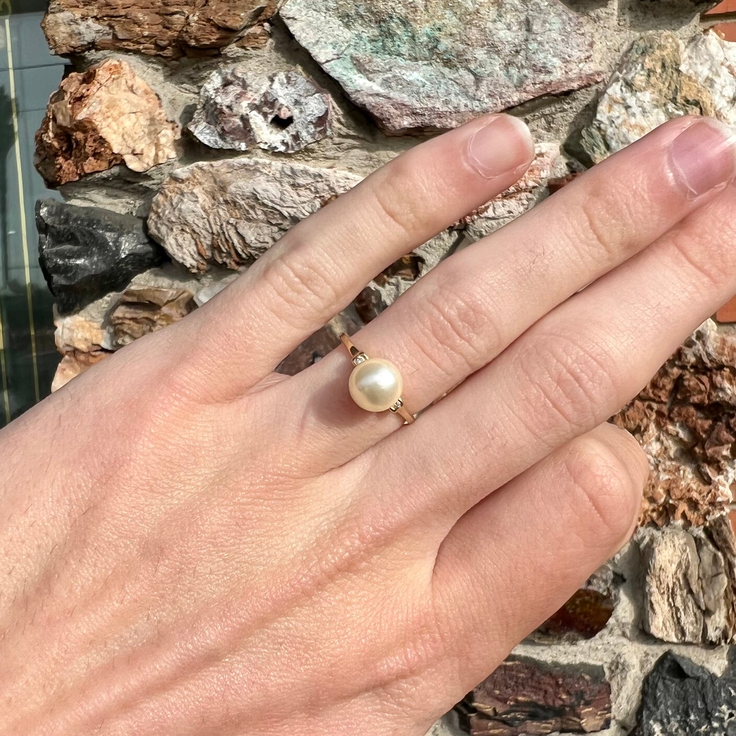 A simple, vintage, yellow gold pearl ring set with two side diamonds.