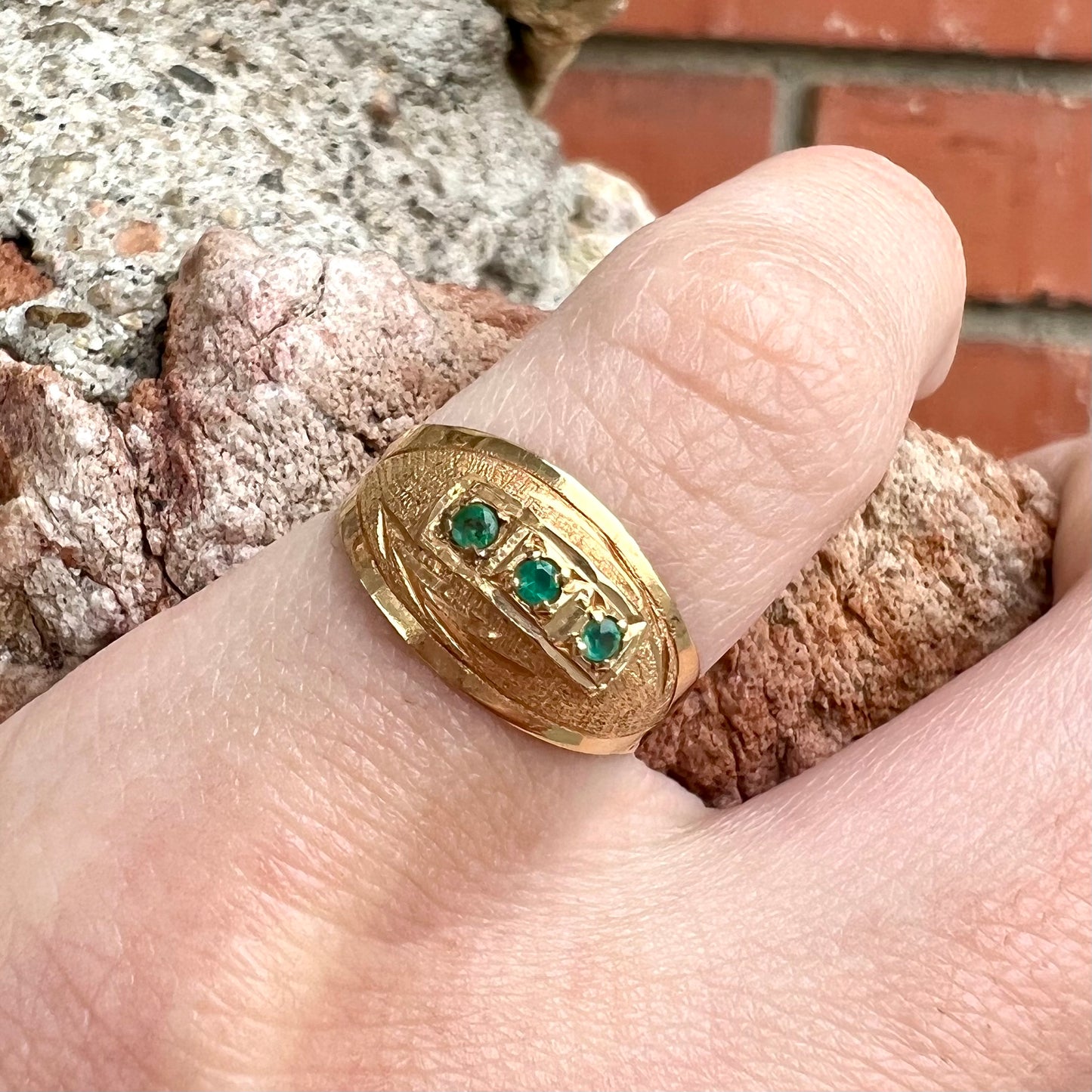 A 1920's style yellow gold three stone round cut emerald ring.