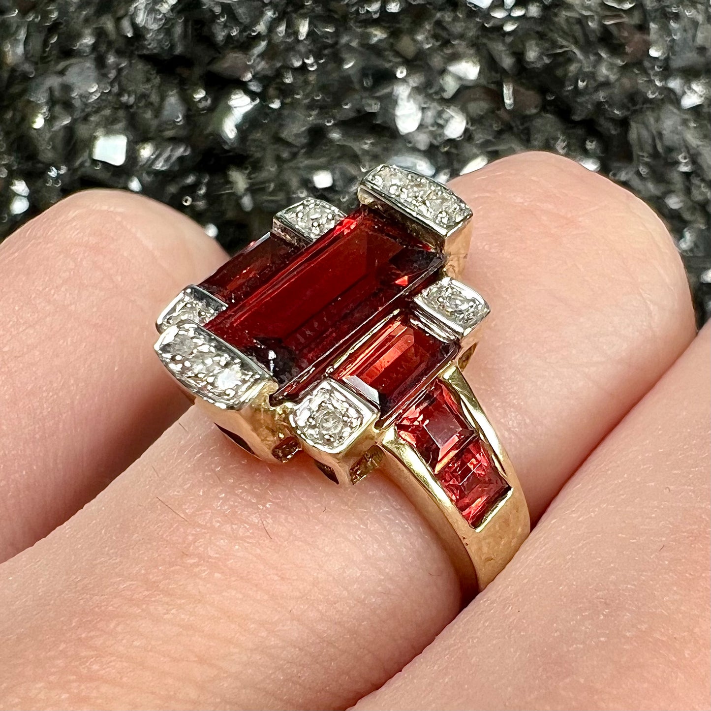 An Art Deco style emerald cut garnet and diamond ring cast in yellow gold.