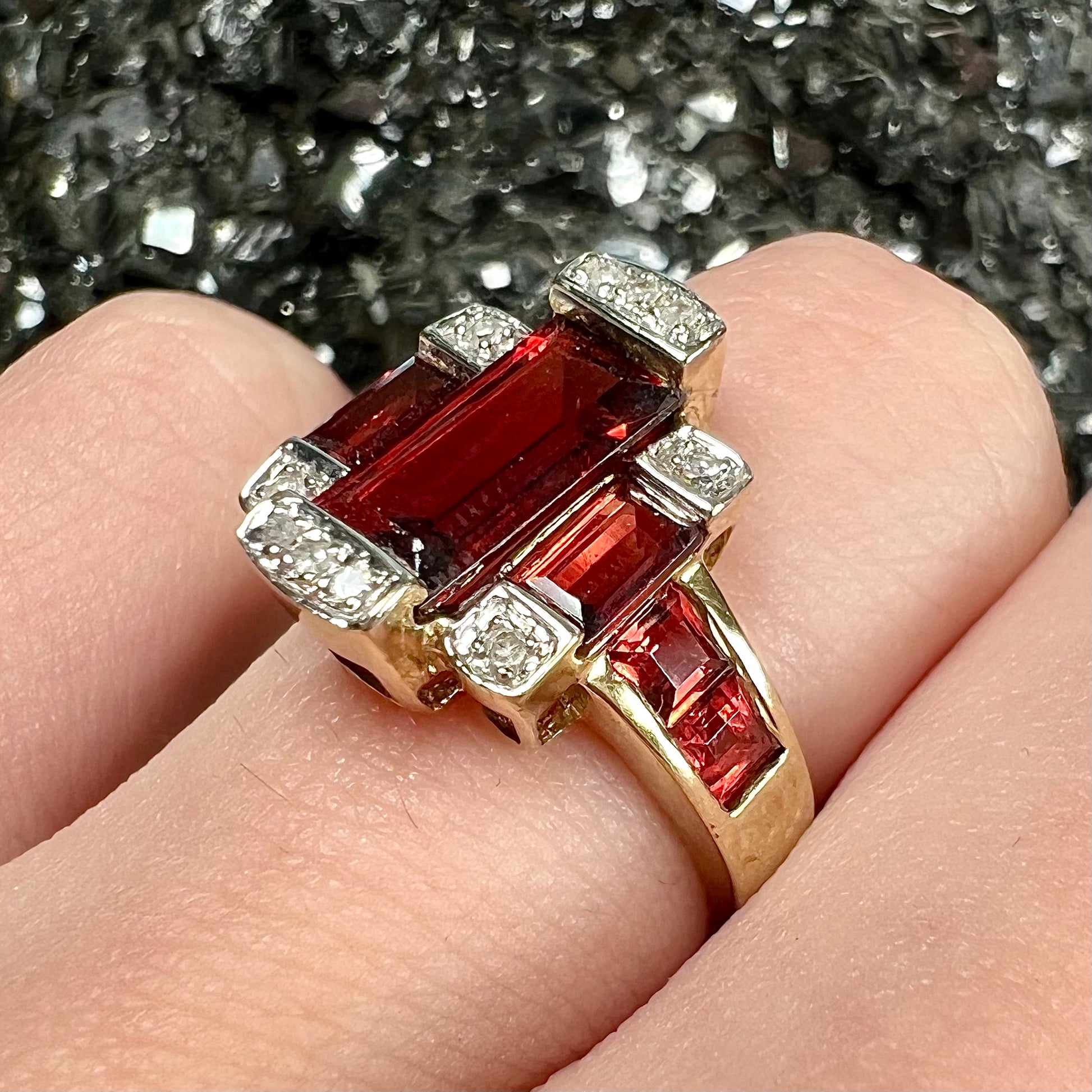 An Art Deco style emerald cut garnet and diamond ring cast in yellow gold.