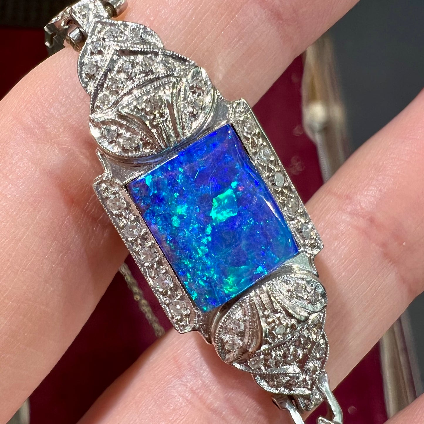 A vintage, art deco style white gold and diamond bracelet set with a rectangular shape black boulder opal stone.