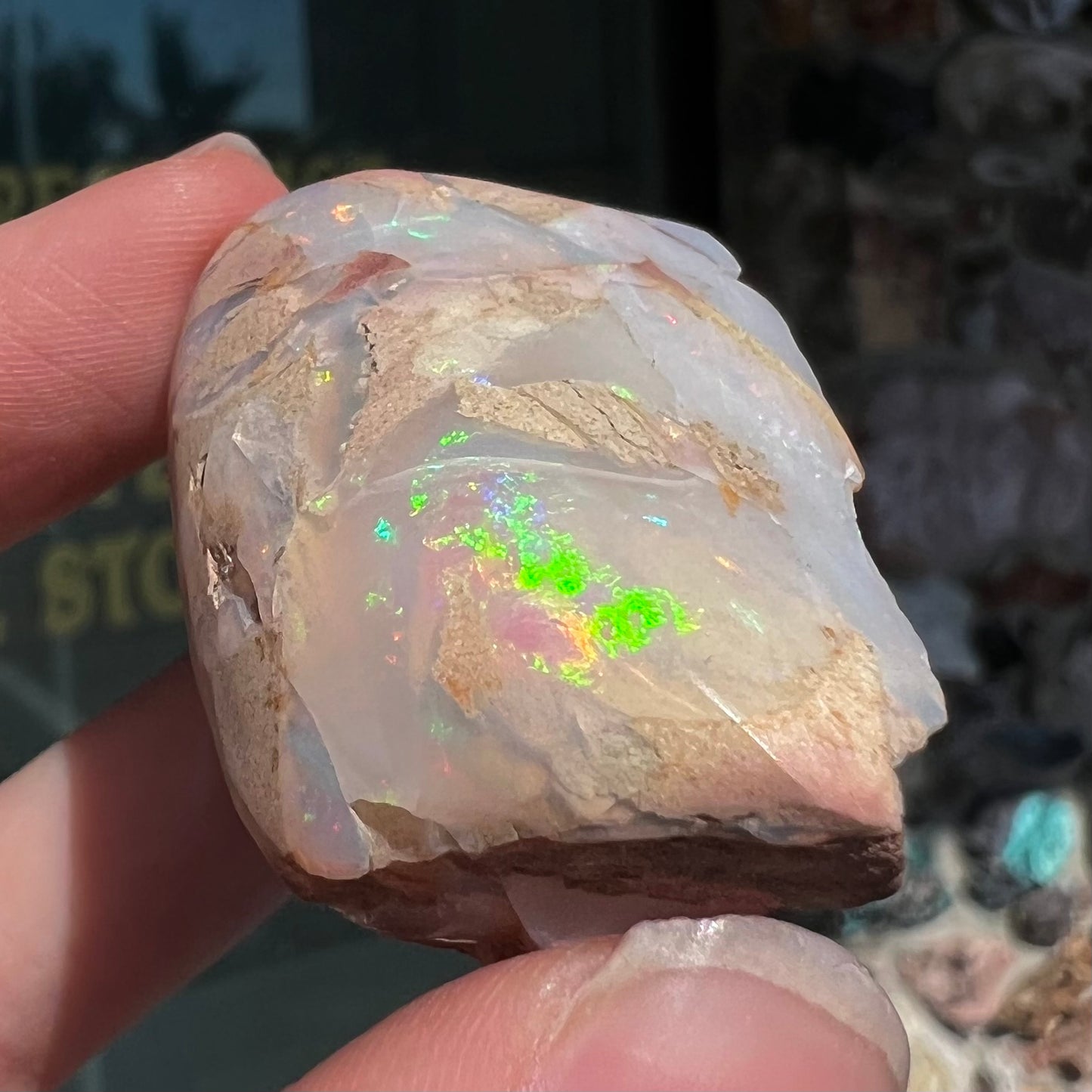 A preform polished matrix opal specimen from White Bluffs, Australia. Predominant colors are red, green, and violet.