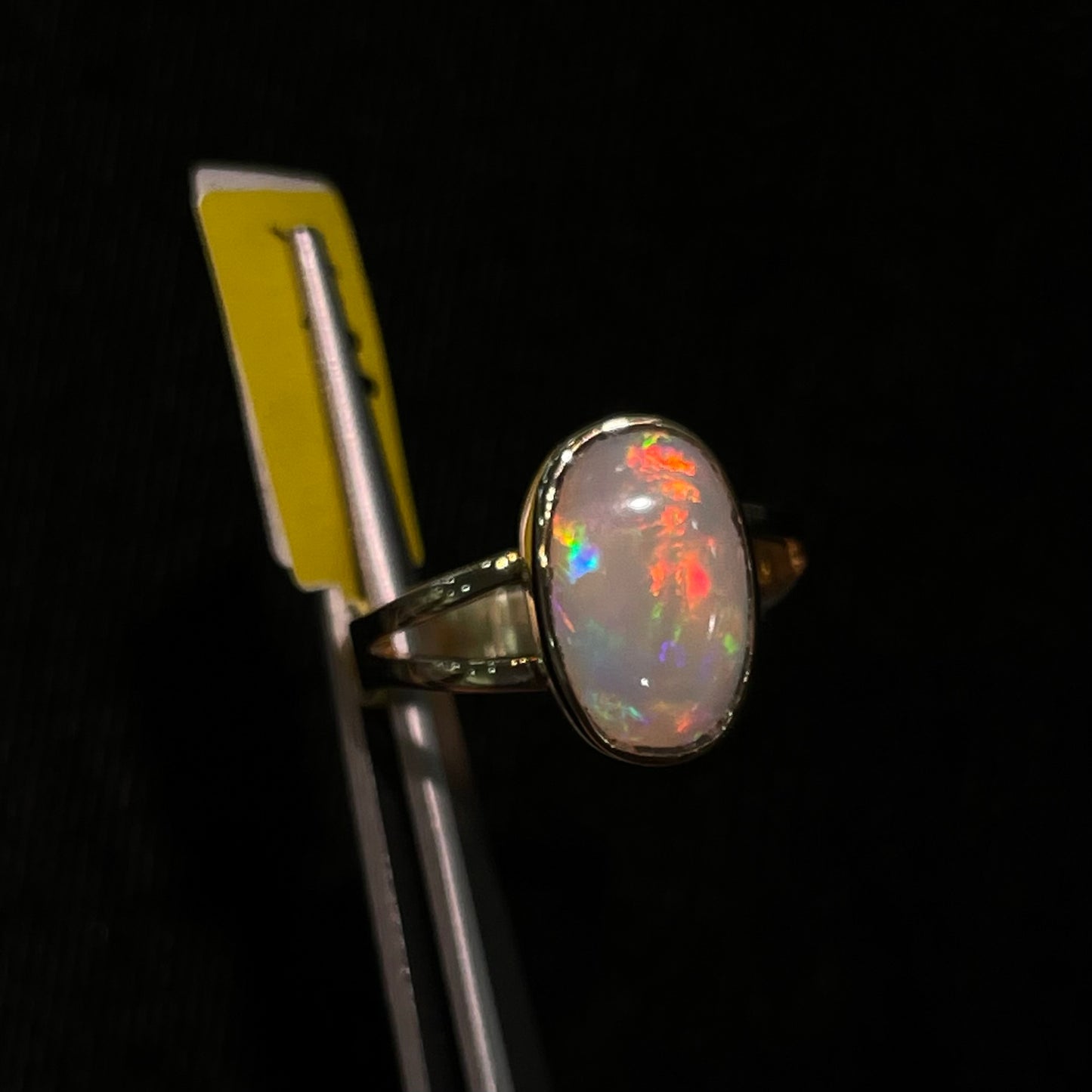 A handmade split shank white opal solitaire ring in yellow gold.