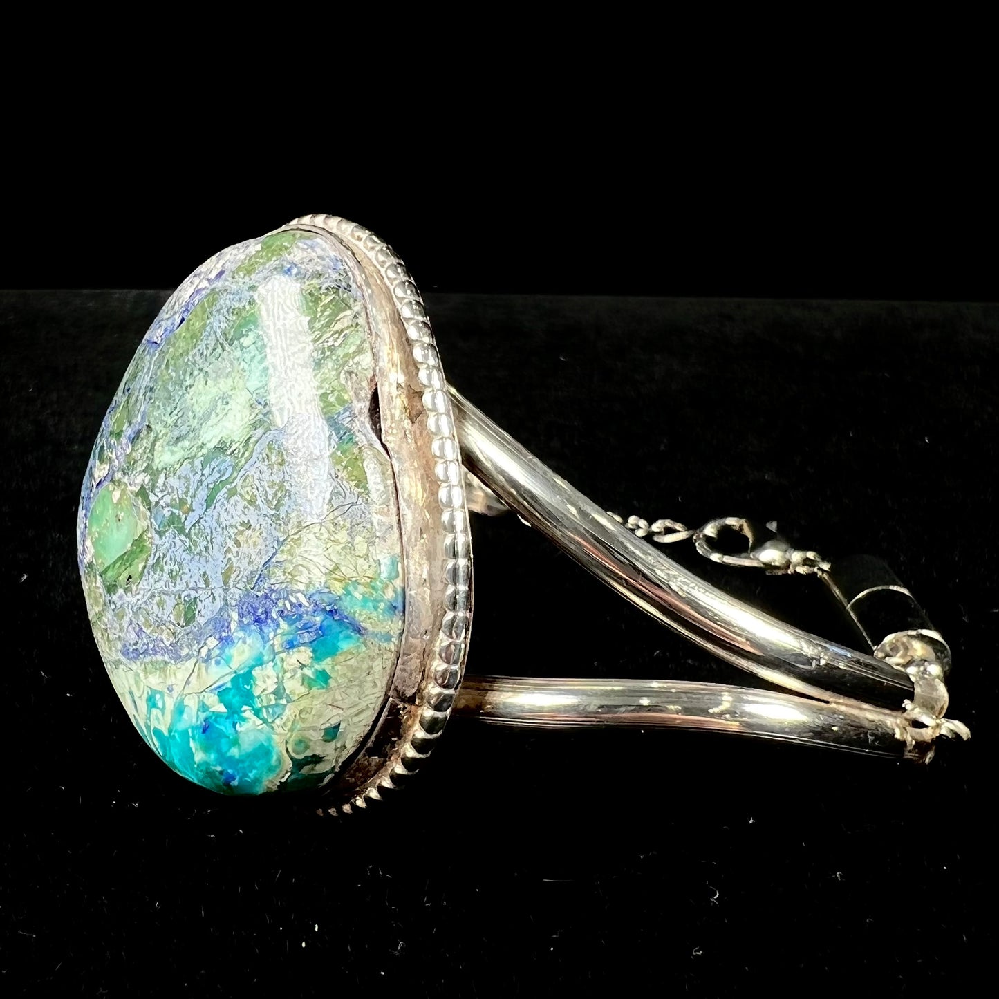 A handmade sterling silver cuff bracelet set with a single stone formed from variscite, chrysocolla, and azurite.