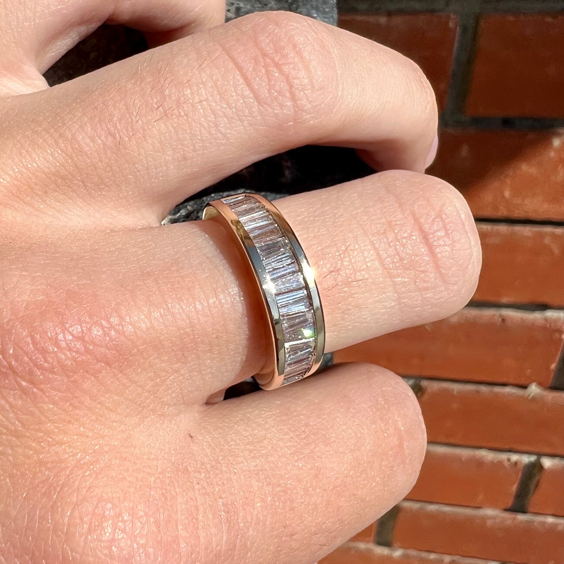 A ladies' yellow gold ring channel set with a row of baguette cut diamonds.