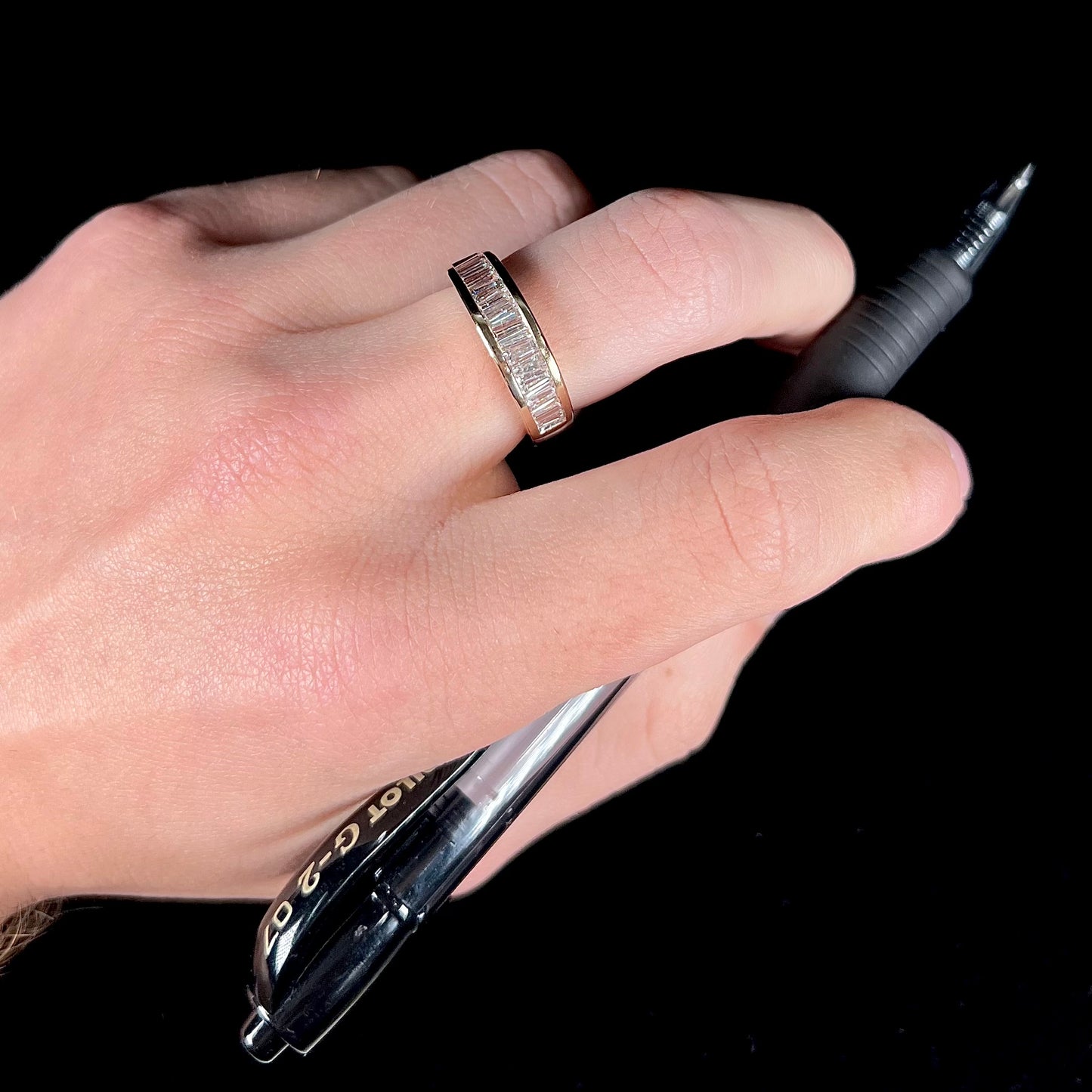 A ladies' yellow gold ring channel set with a row of baguette cut diamonds.