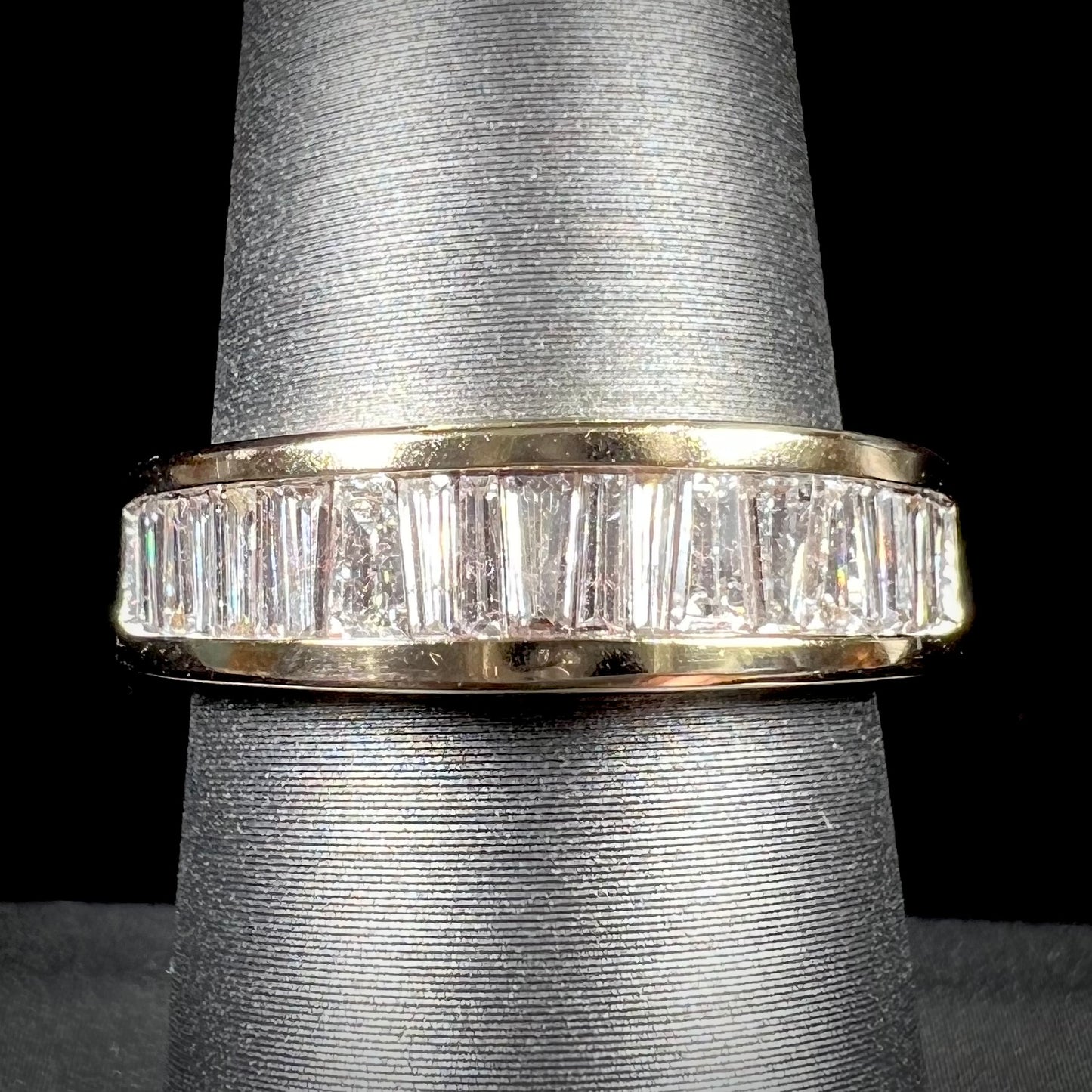 A ladies' yellow gold ring channel set with a row of baguette cut diamonds.
