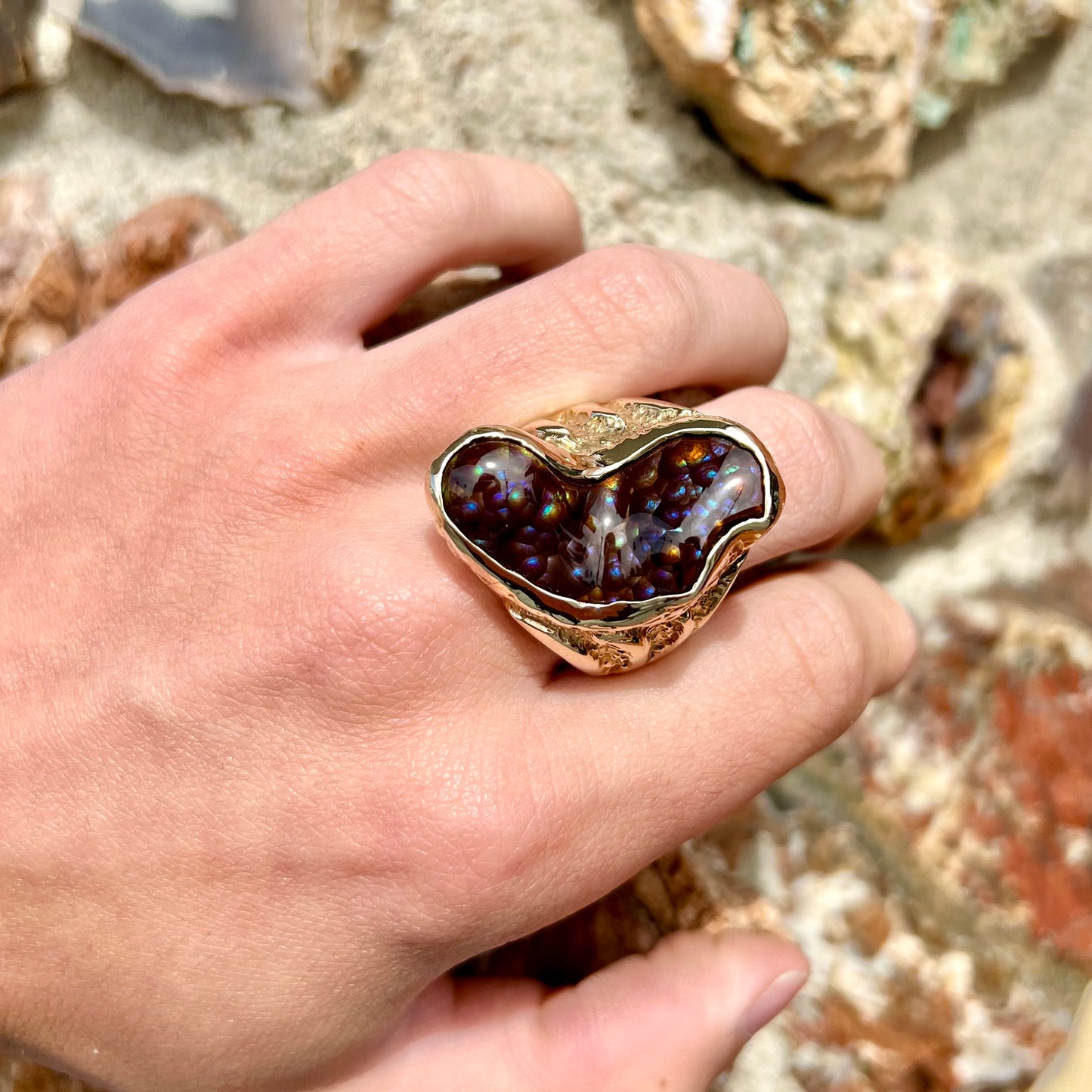 A men's Deer Creek fire agate solitaire ring cast in yellow gold. The stone is predominantly purple.