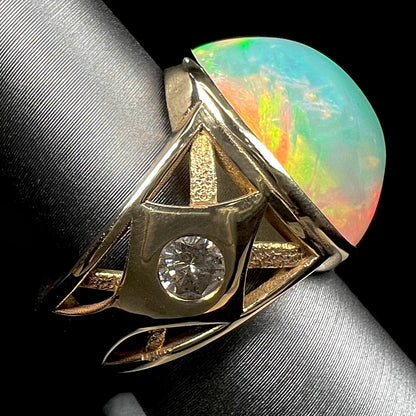 A custom yellow gold men's ring set with two diamonds and a large oval cabochon cut opal from Ethiopia, Africa.