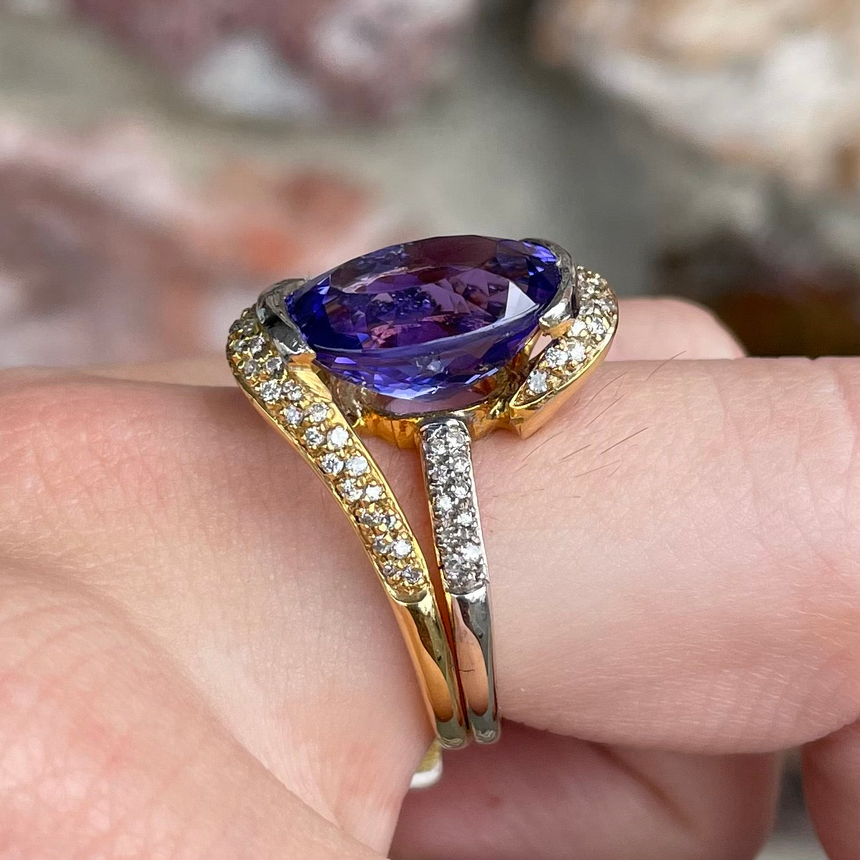 A large, oval cut blue tanzanite set in a two tone yellow and white gold diamond ring.