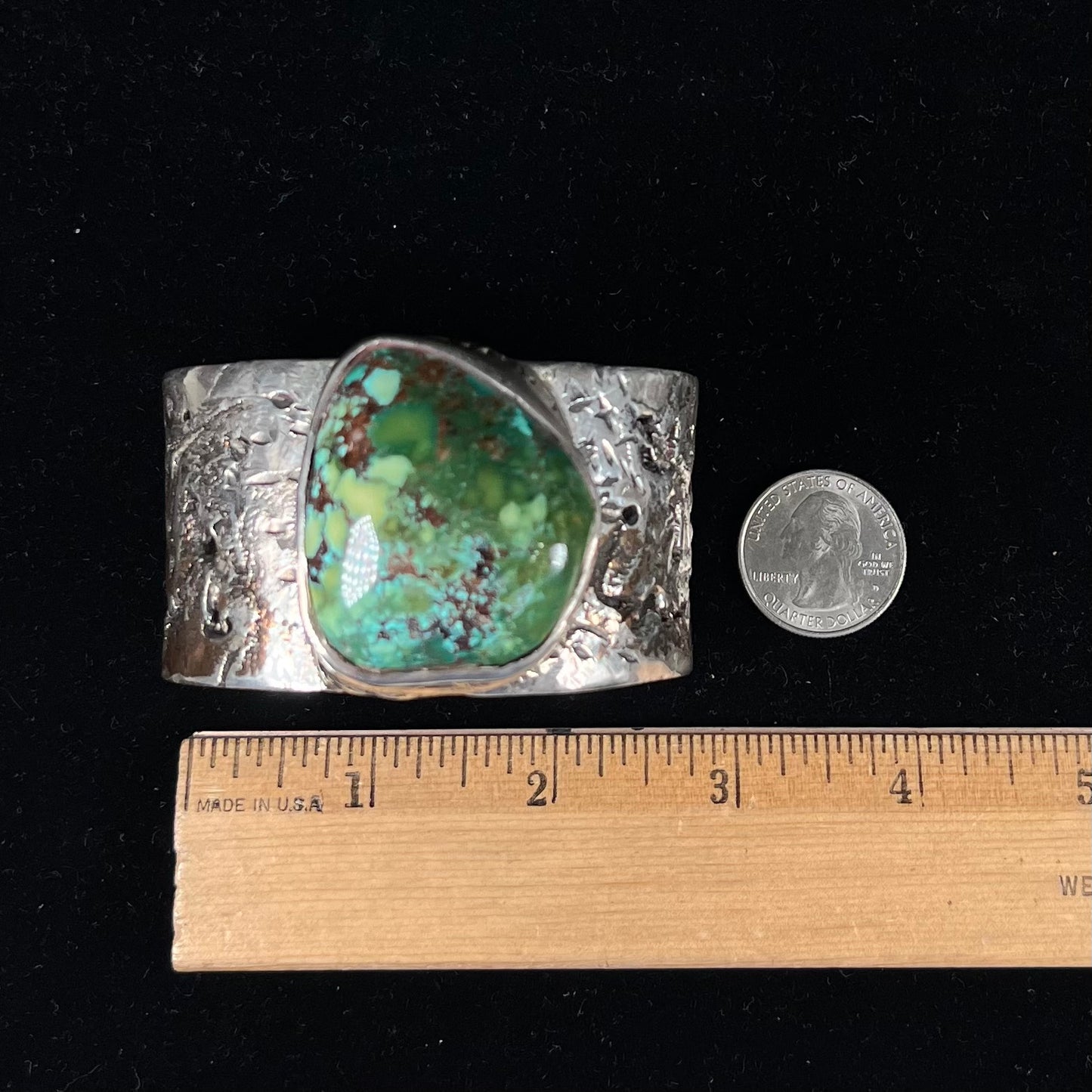A men's sterling silver cuff bracelet infused with copper and set with a green turquoise stone from Carico Lake, Nevada.