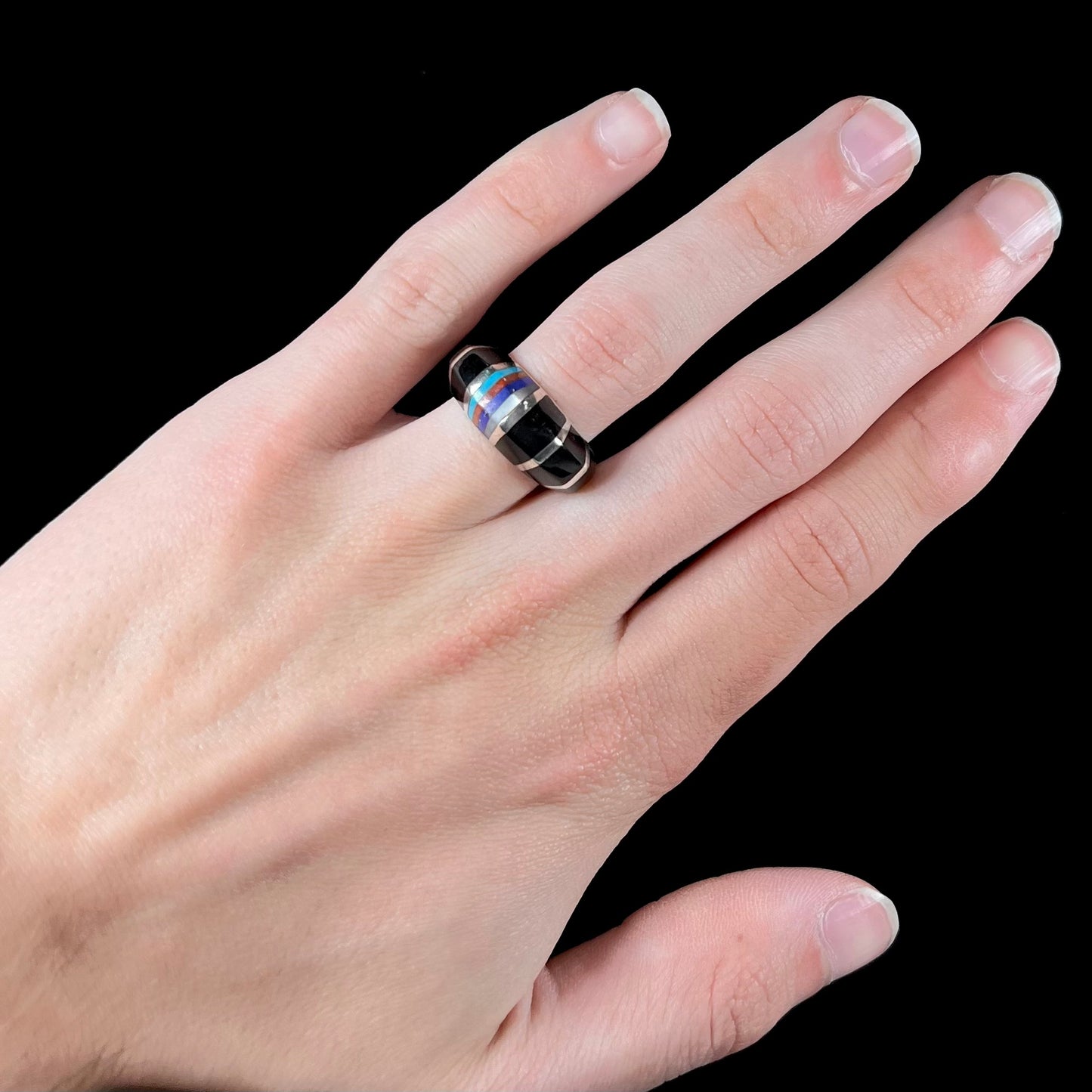 A sterling silver ring inlaid with onyx, turquoise, coral, lapis lazuli, and mother of pearl stones.