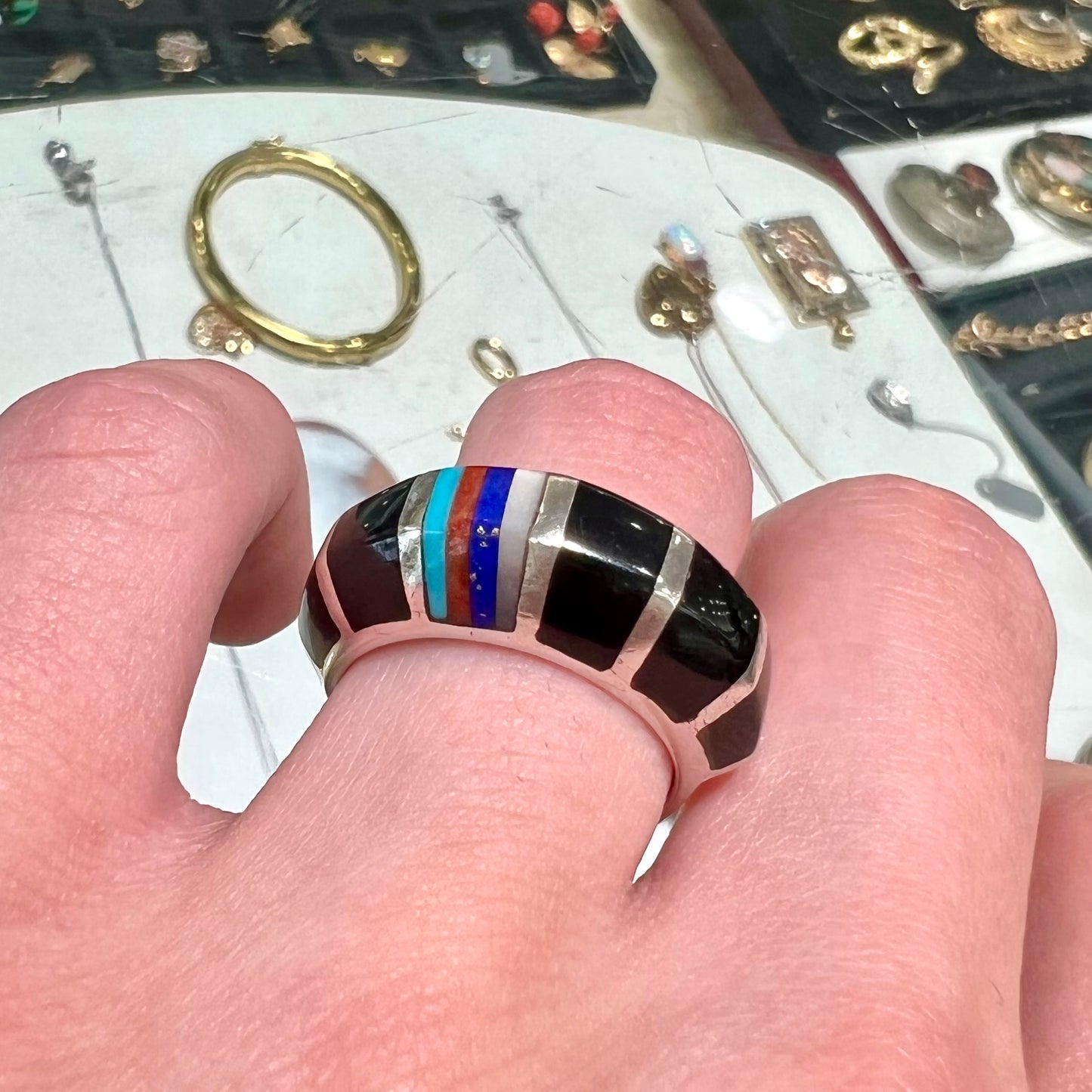 A sterling silver ring inlaid with onyx, turquoise, coral, lapis lazuli, and mother of pearl stones.