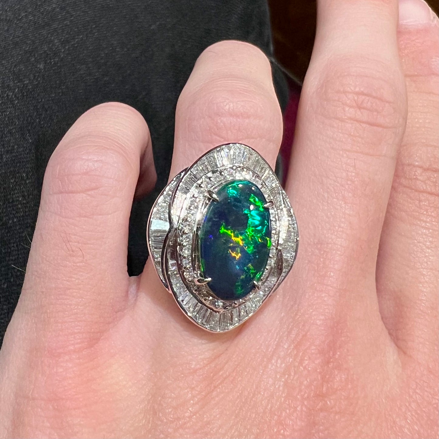 A ladies' platinum diamond halo ring set with a natural black opal stone from Lightning Ridge, Australia.