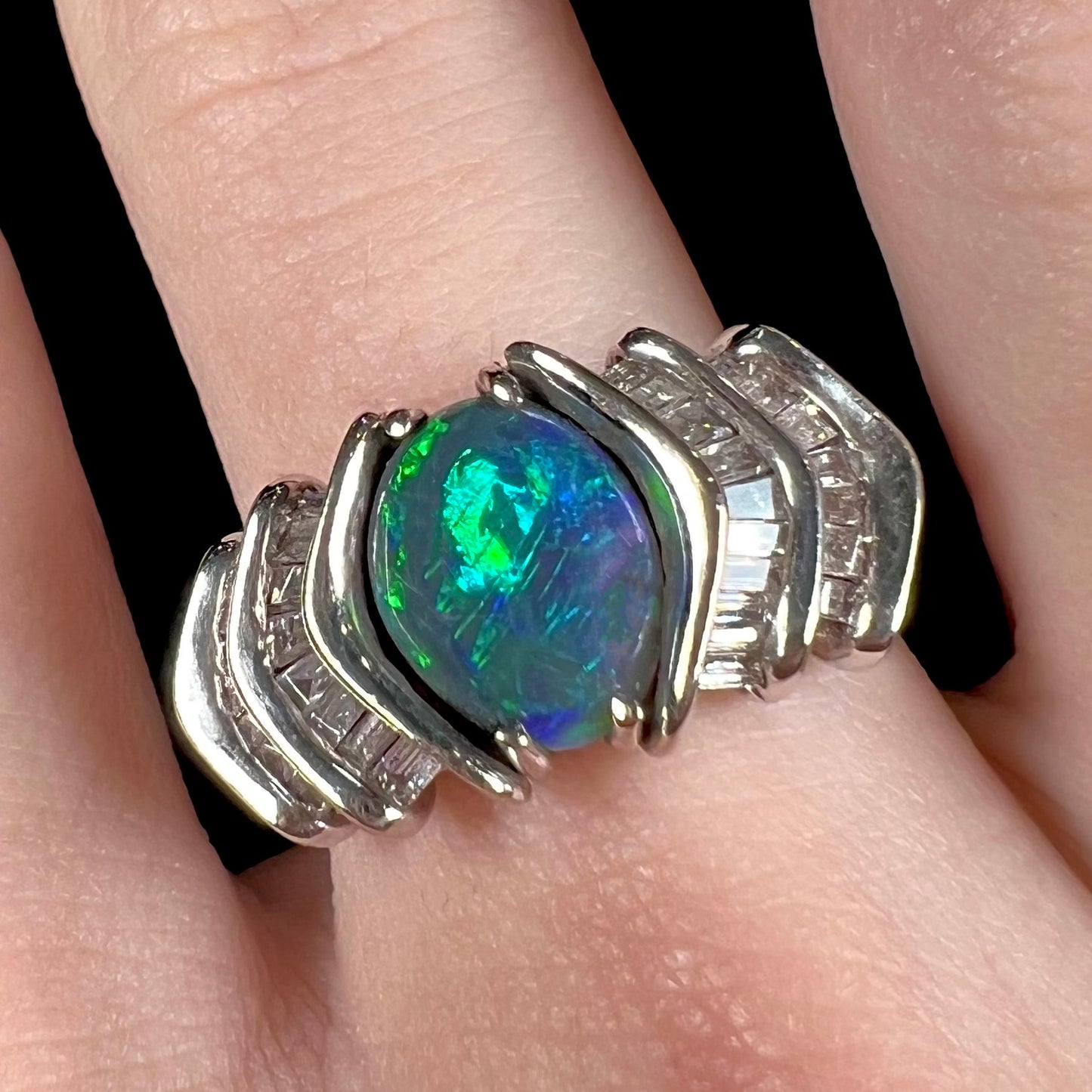 A white gold ring set with a Lightning Ridge natural black opal and baguette cut diamonds.