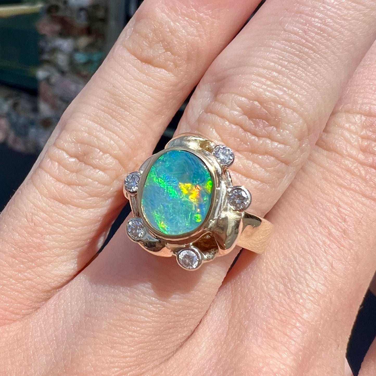 A ladies' yellow gold oval cut natural black opal ring set with five round accent diamonds.