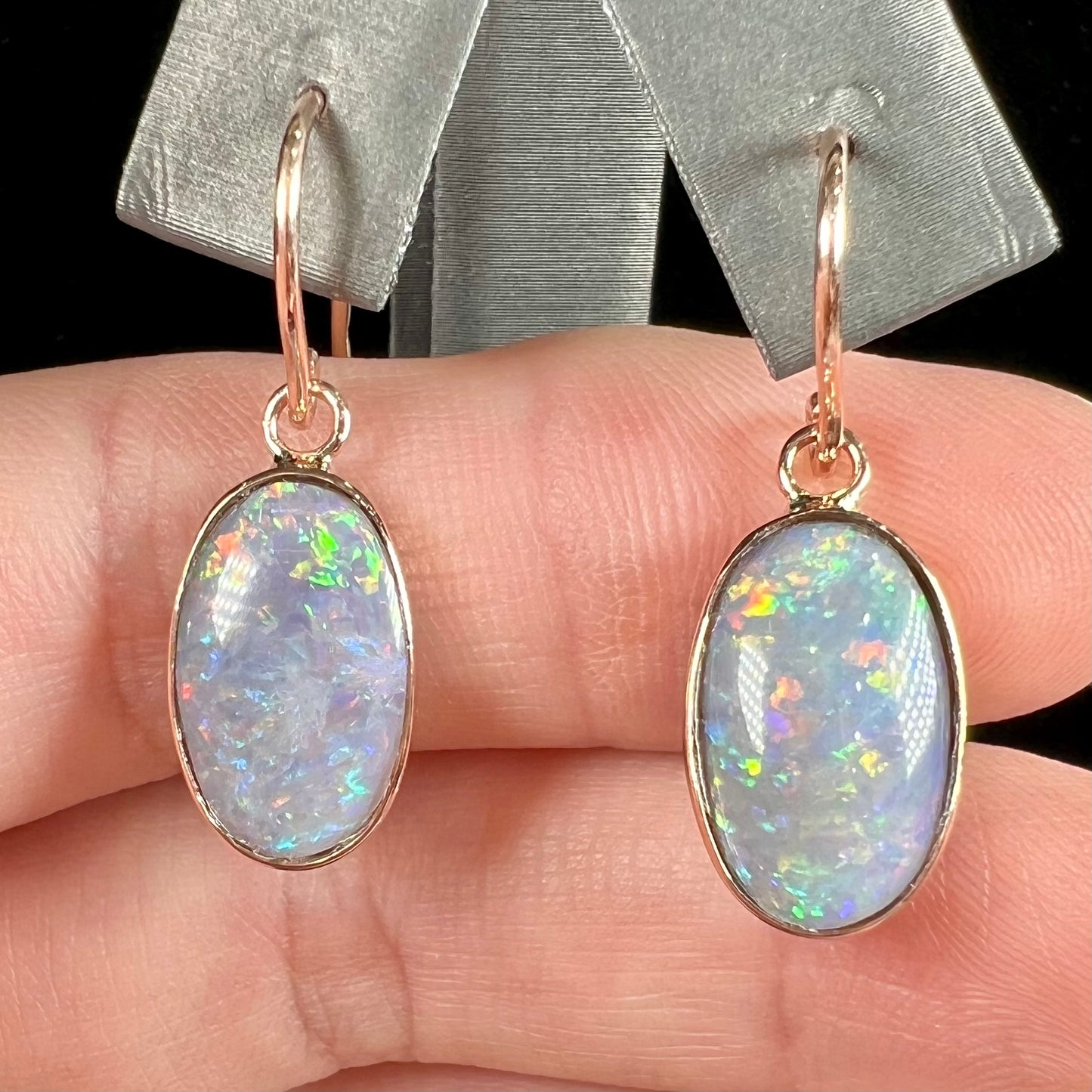 A pair of rose gold dangle earrings set with black opalized shell.