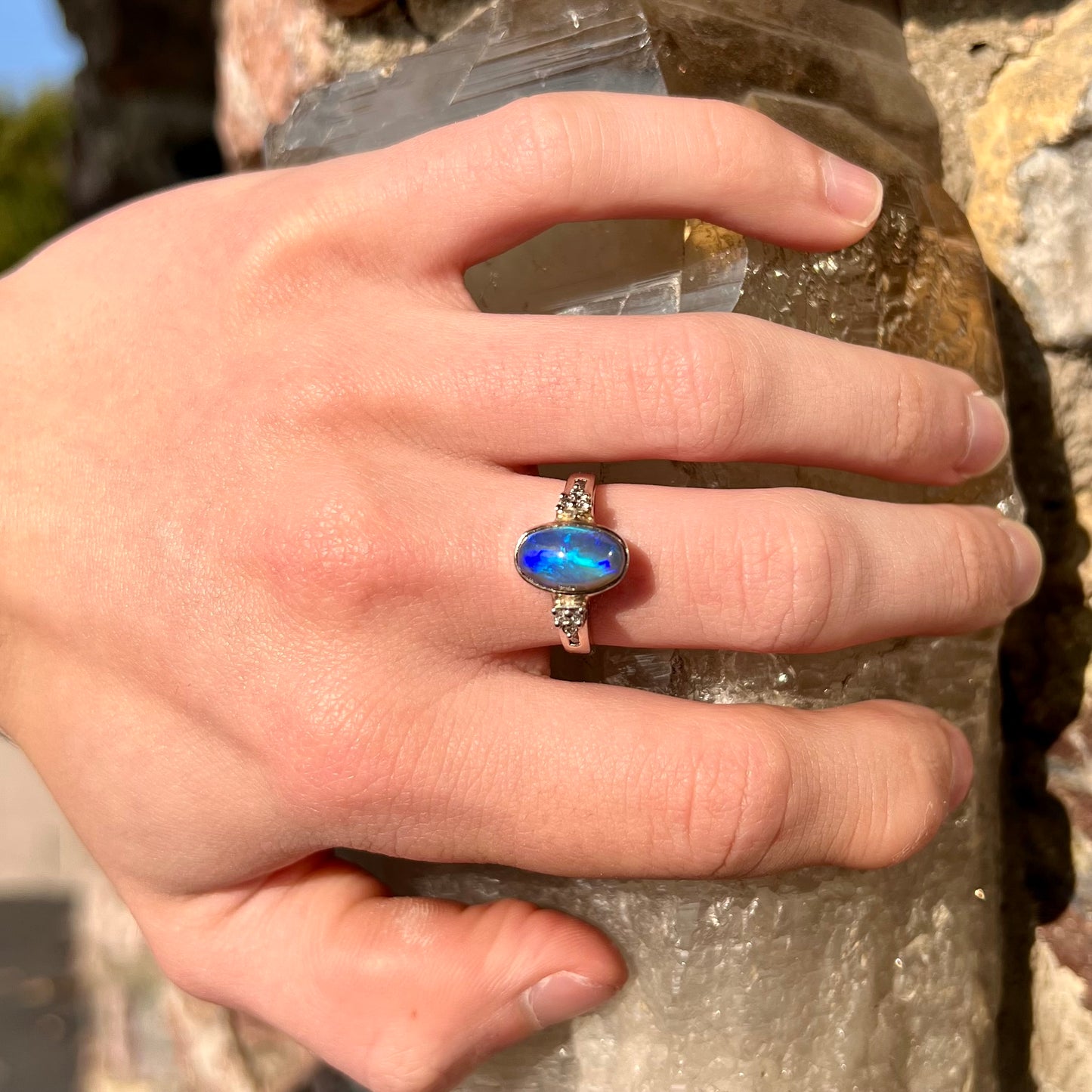 A white gold ring set with a Lightning Ridge black opal and diamond accents. The opal displays a cat's eye pattern.