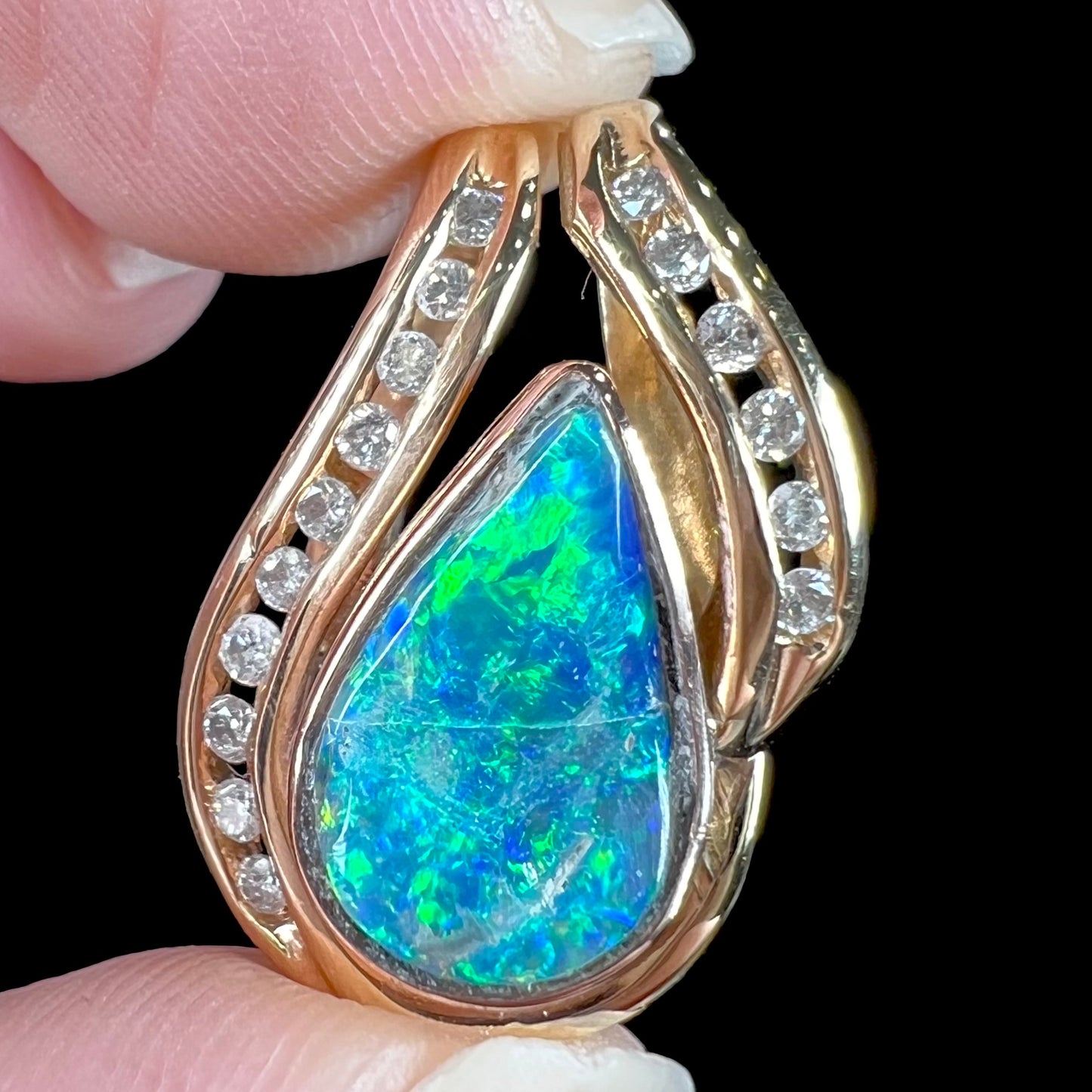 A ladies' yellow gold slider pendant set with a pear shaped Lightning Ridge, Australian black crystal opal and diamonds.