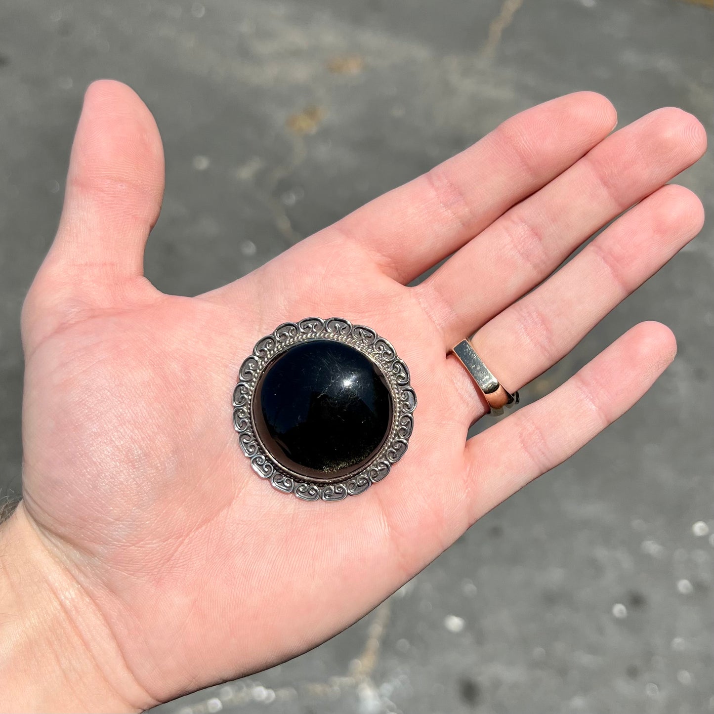 A sterling silver pendant/brooch bezel set with a round cabochon cut black sheen obsidian stone.