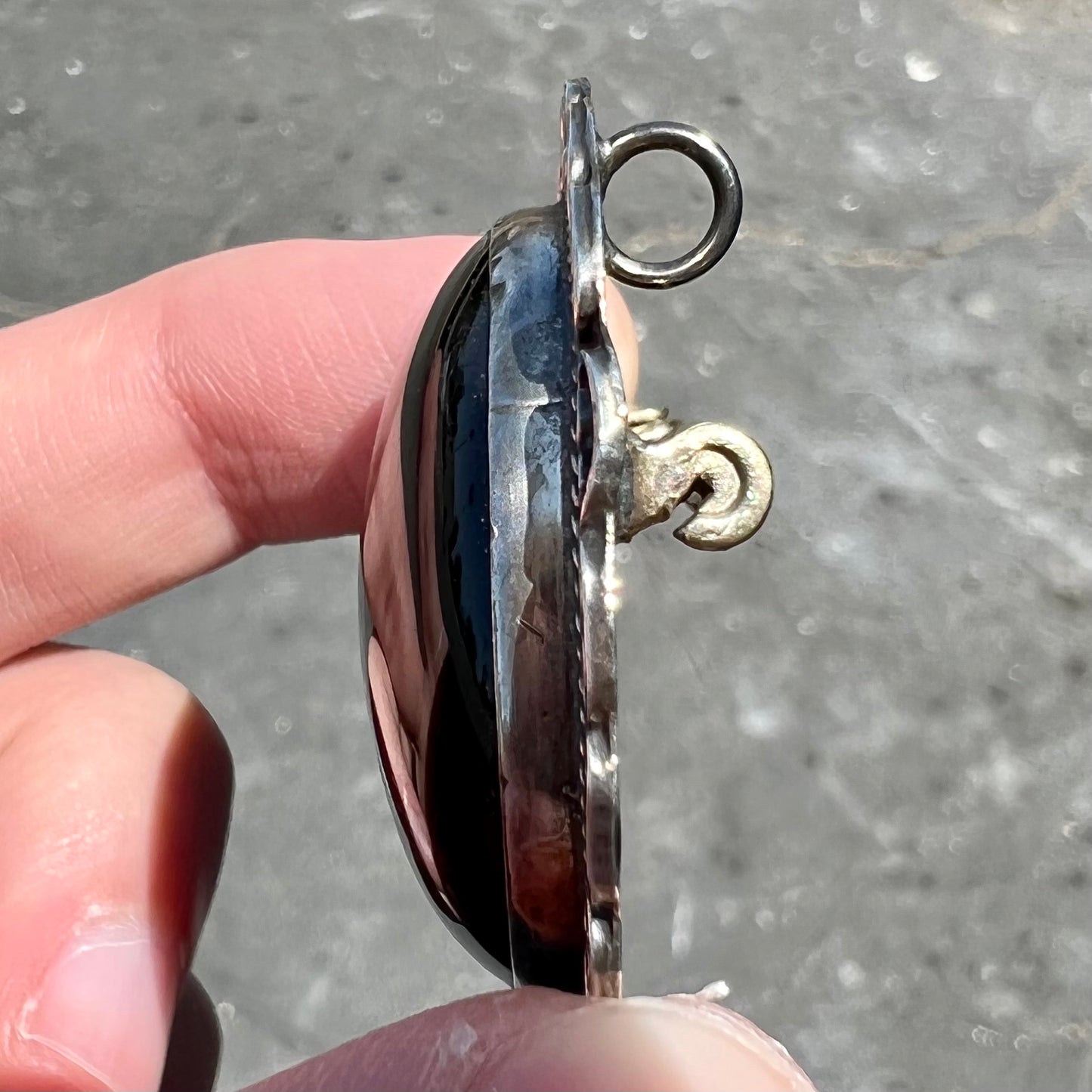 A sterling silver pendant/brooch bezel set with a round cabochon cut black sheen obsidian stone.
