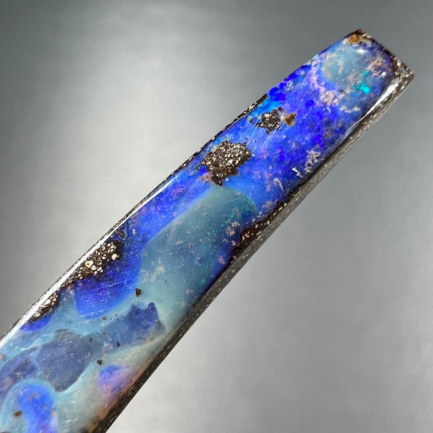 A loose, polished Quilpie boulder opal stone from Australia. The stone is predominantly blue.