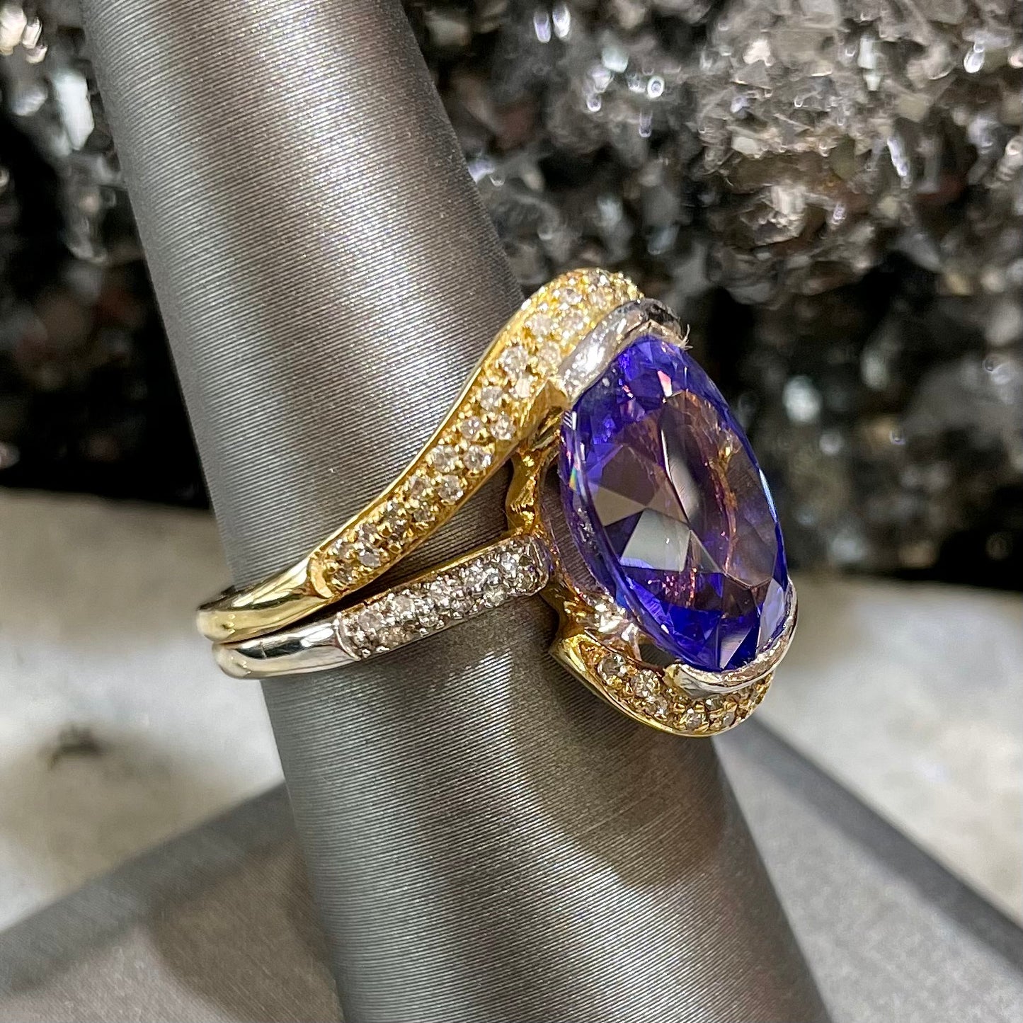 A large, oval cut blue tanzanite set in a two tone yellow and white gold diamond ring.