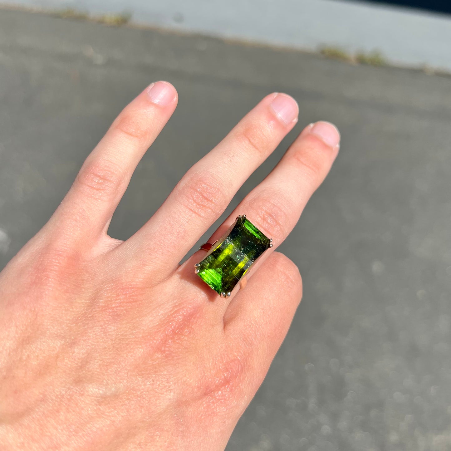 A faceted step-cut dark green tourmaline basket set solitaire ring cast in yellow gold.