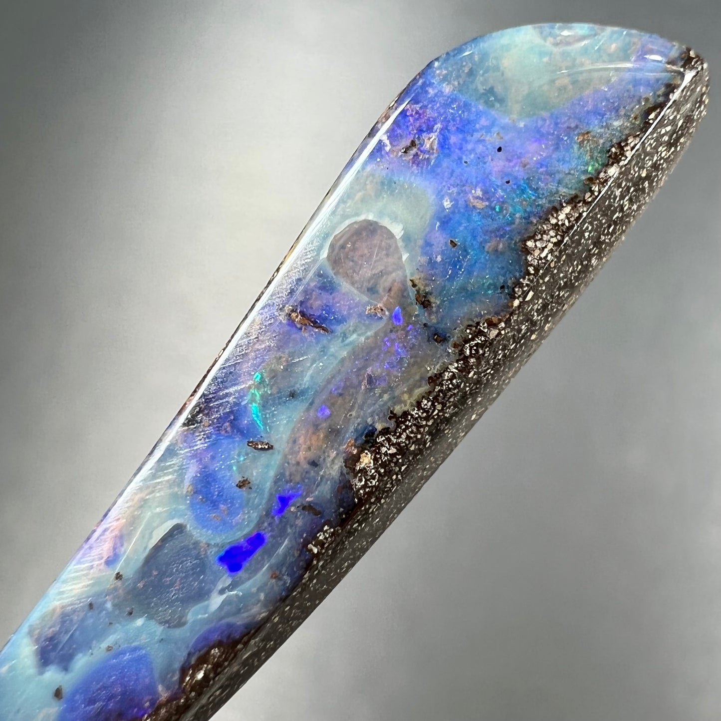 A loose, polished Quilpie boulder opal stone from Australia. The stone is predominantly blue.