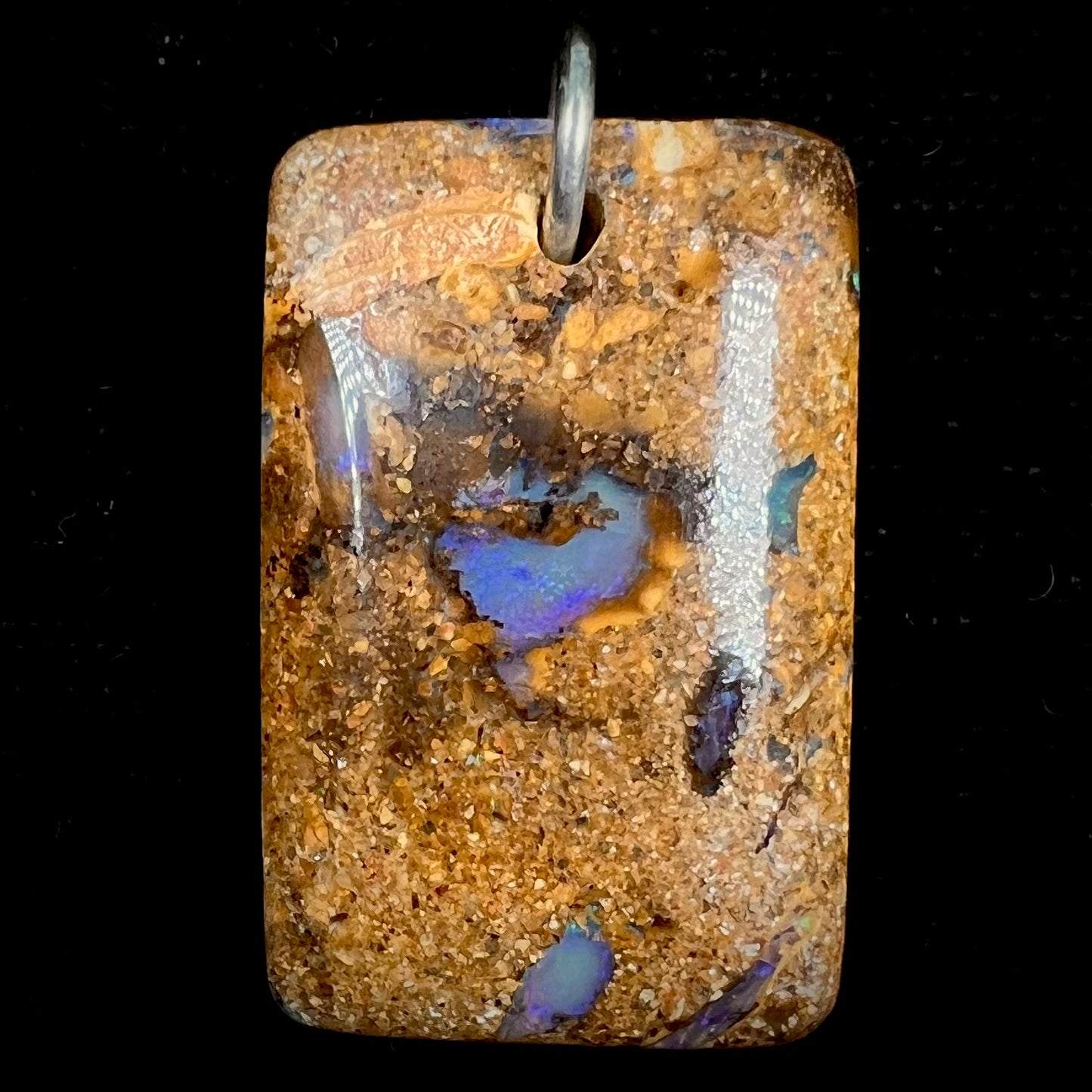 A drilled boulder opal stone with a sterling silver ring through the hole to be worn as a pendant.