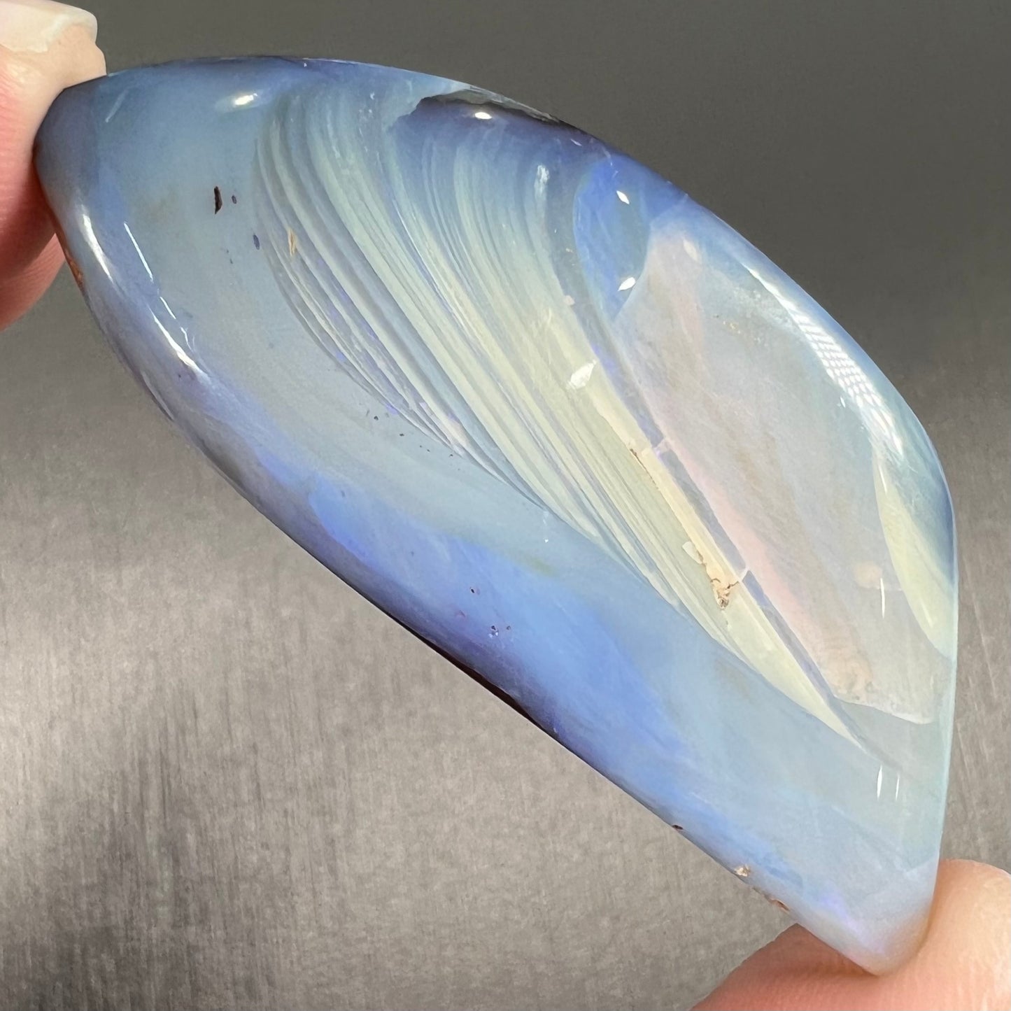 A loose, polished blue boulder opal stone from Queensland, Australia.