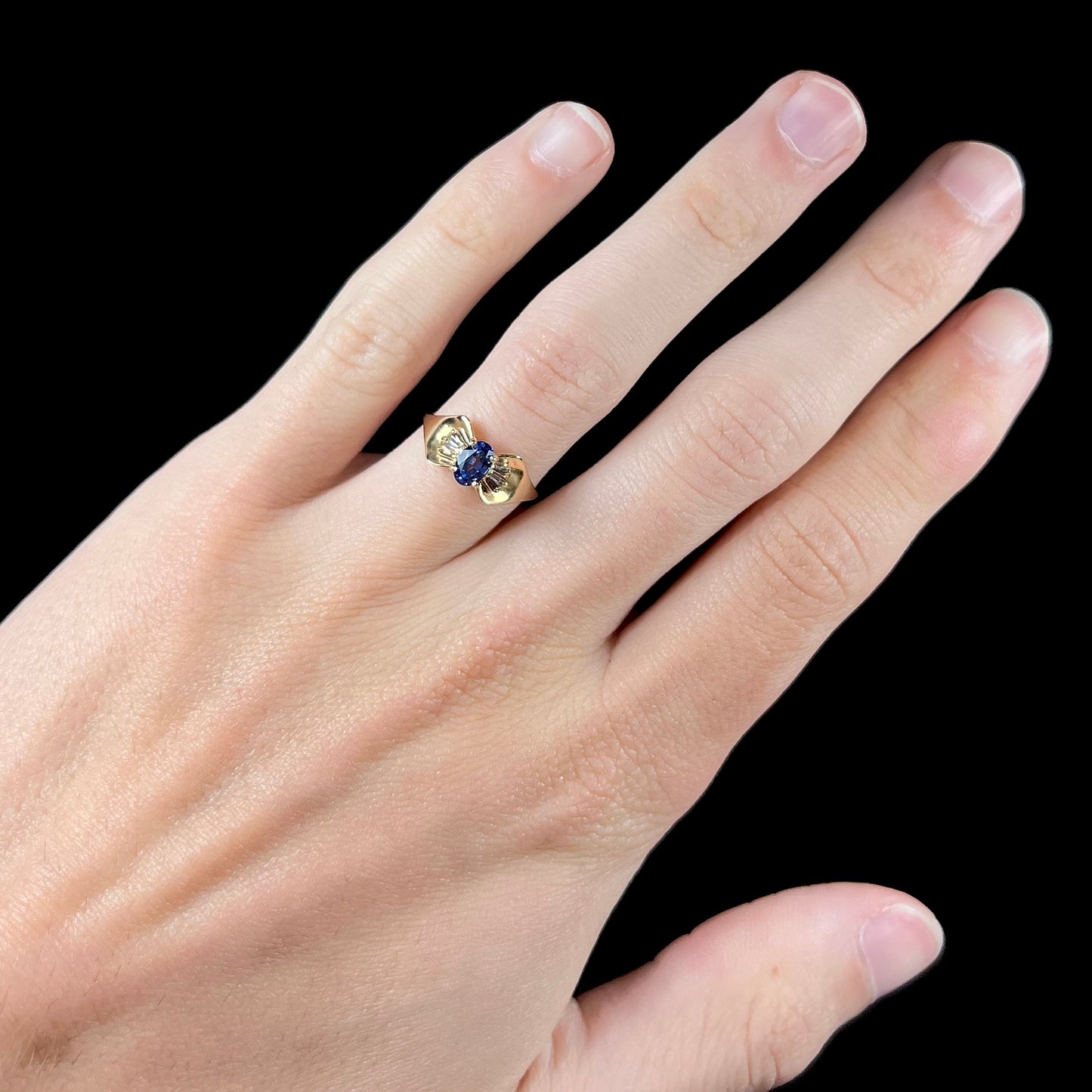 A natural blue sapphire and diamond baguette ring cast in yellow gold.