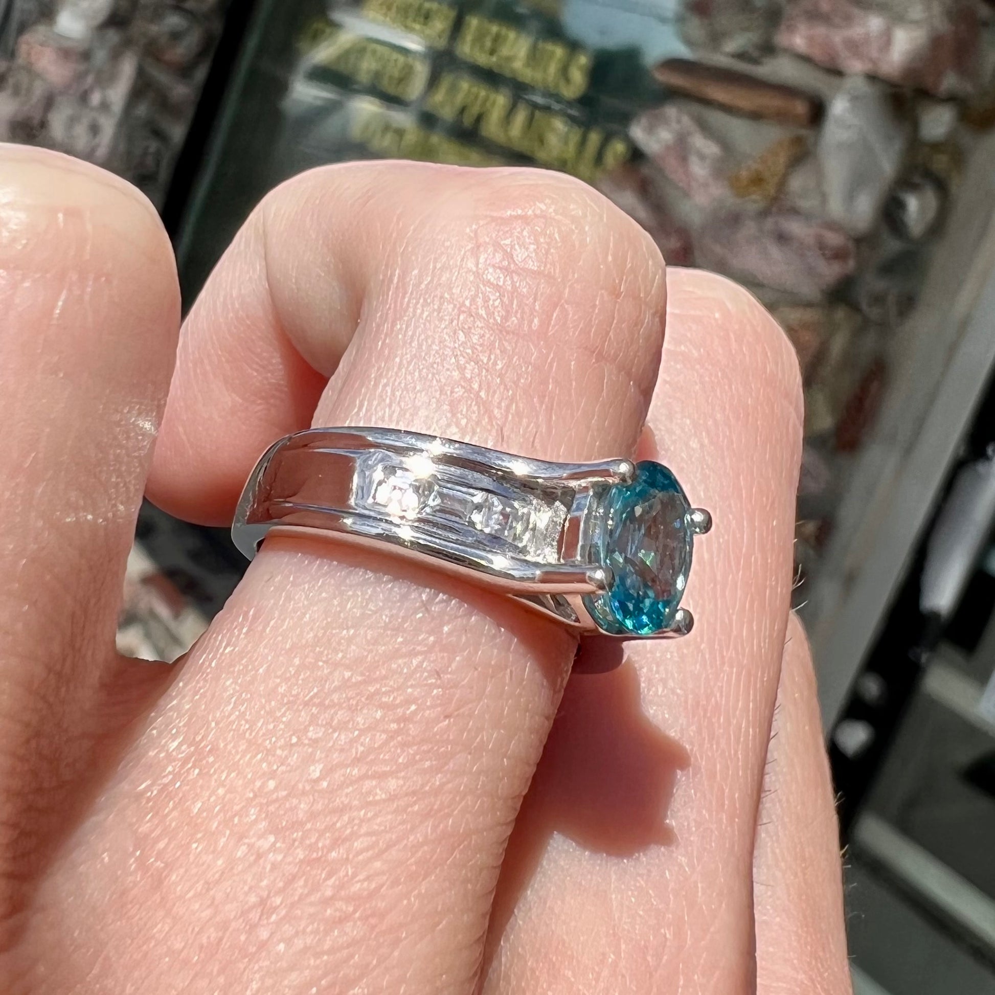A sterling silver ring set with an oval cut blue zircon center stone and channel set white zircon accents.