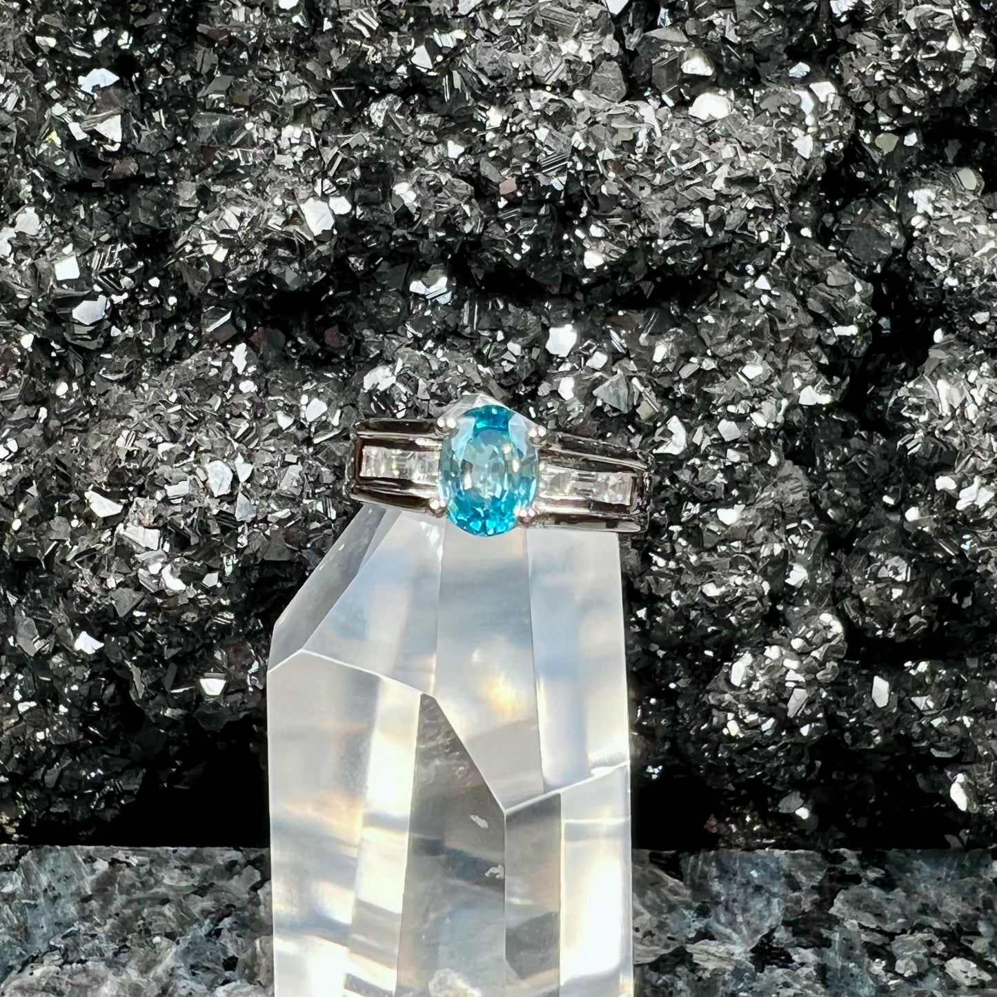 A sterling silver ring set with an oval cut blue zircon center stone and channel set white zircon accents.
