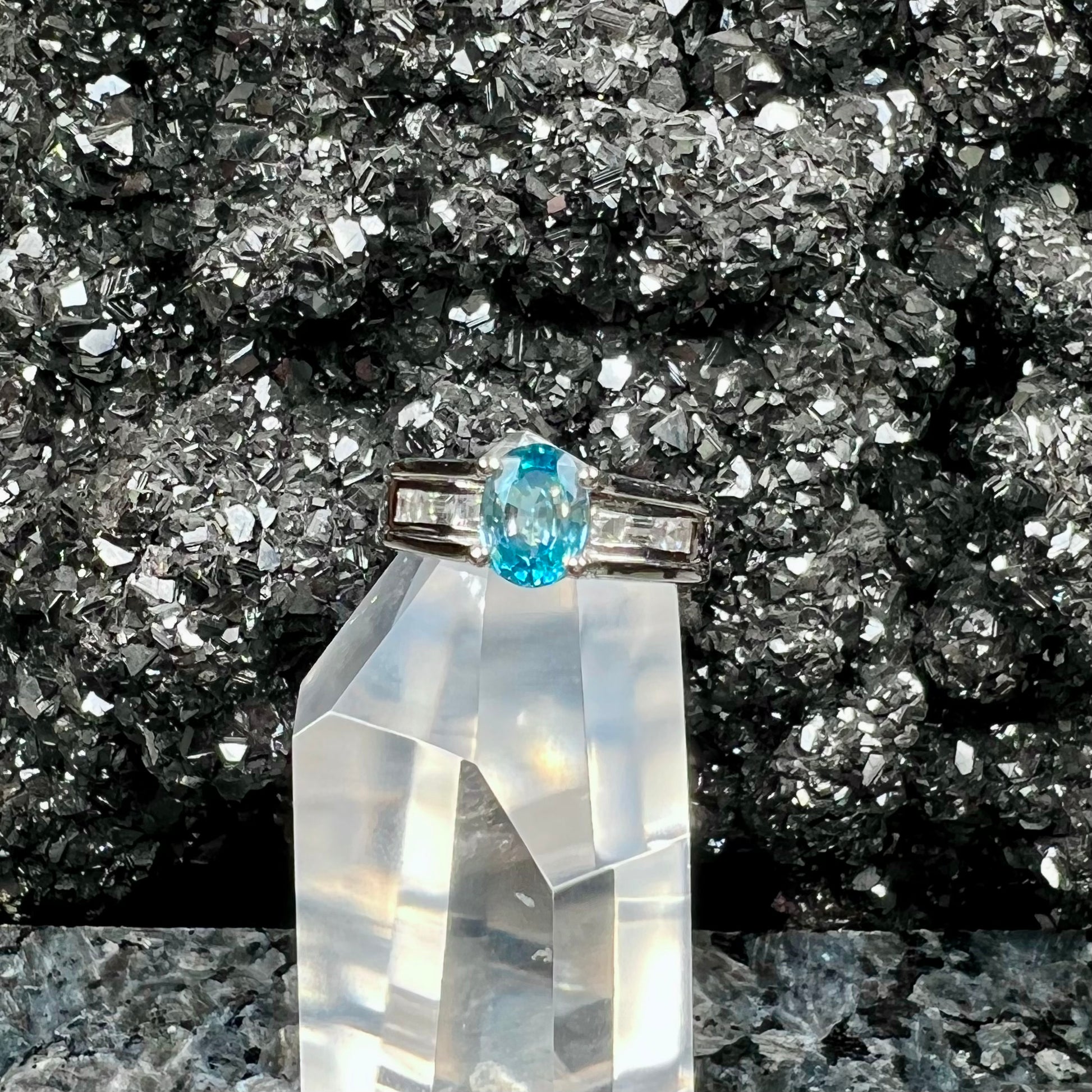A sterling silver ring set with an oval cut blue zircon center stone and channel set white zircon accents.
