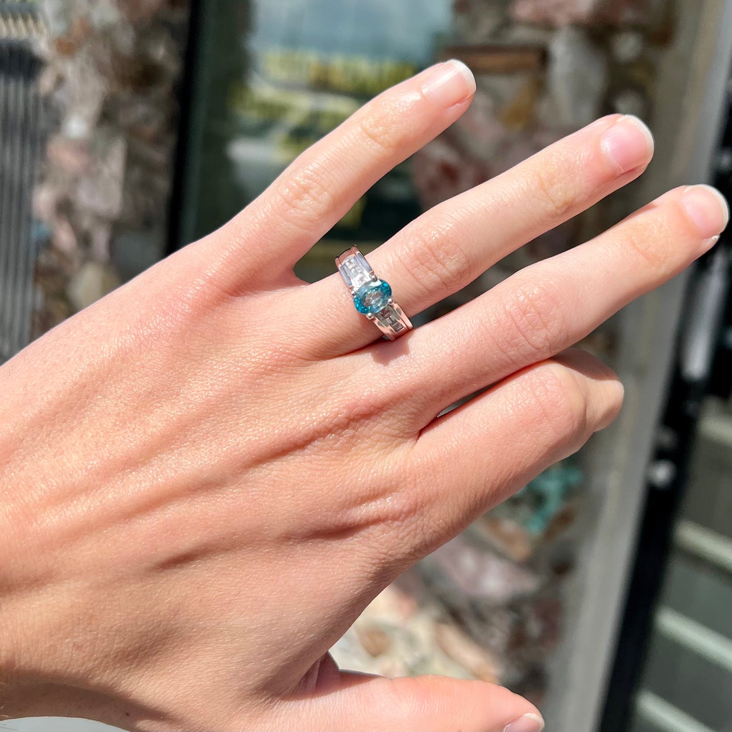 A sterling silver ring set with an oval cut blue zircon center stone and channel set white zircon accents.