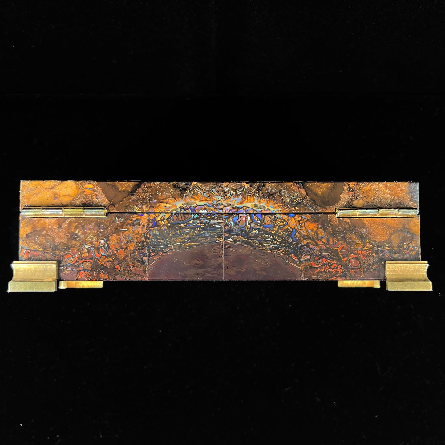 A stone box made from Koroit, Australian boulder opal featuring the motif of a dragonfly and cricket made from sterling silver, set with yellow diamonds, an emerald, and a crystal opal.