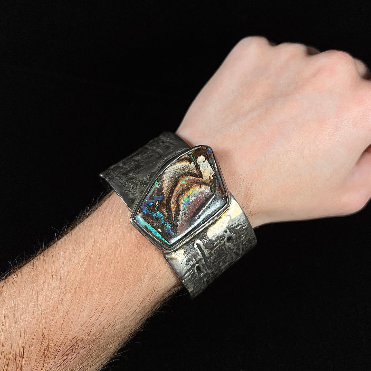 A men's sterling silver cuff bracelet set with an Australian Koroit boulder opal stone, handmade by Sam Yah.