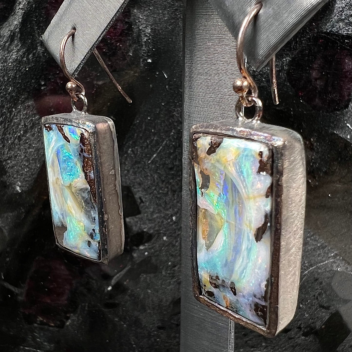 A pair of handmade sterling silver boulder opal earrings. The earrings dangle from French wire hooks.
