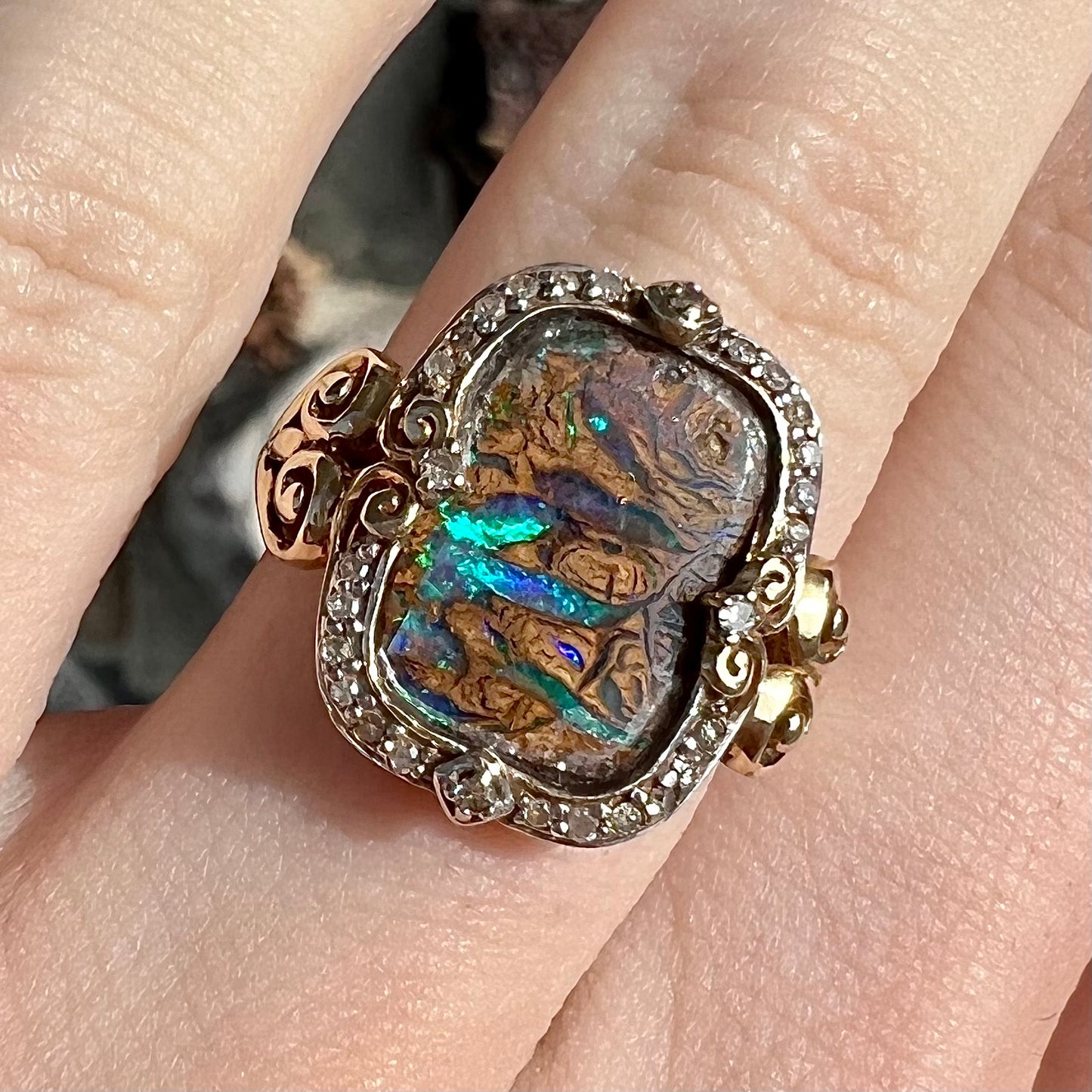 Striped Koroit boulder opal set in a filigree 14k yellow gold setting with diamonds. The filigree has a heart pattern.